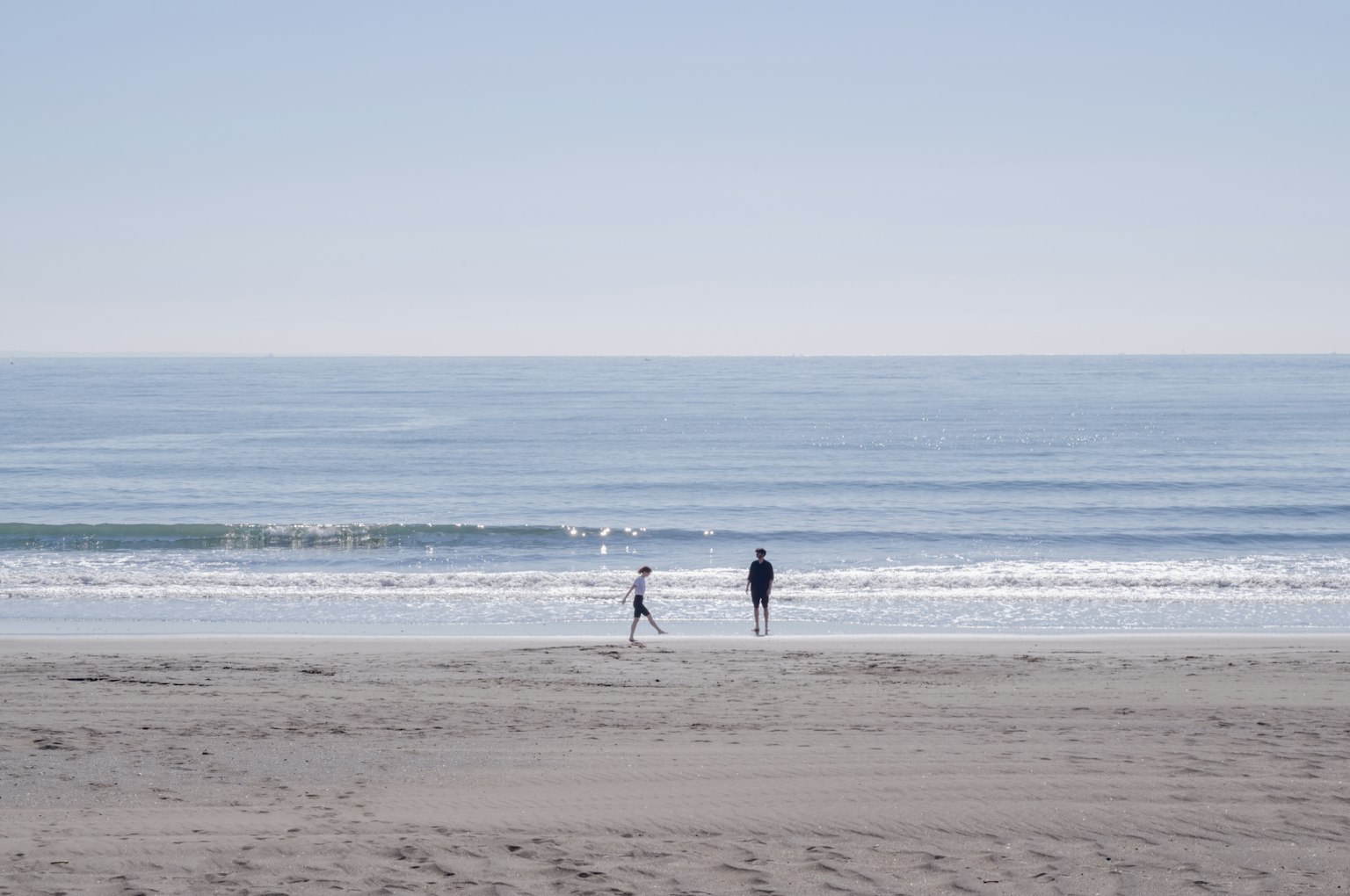 Silhouette d'un parent et d'un enfant jouant au bord d'une mer calme