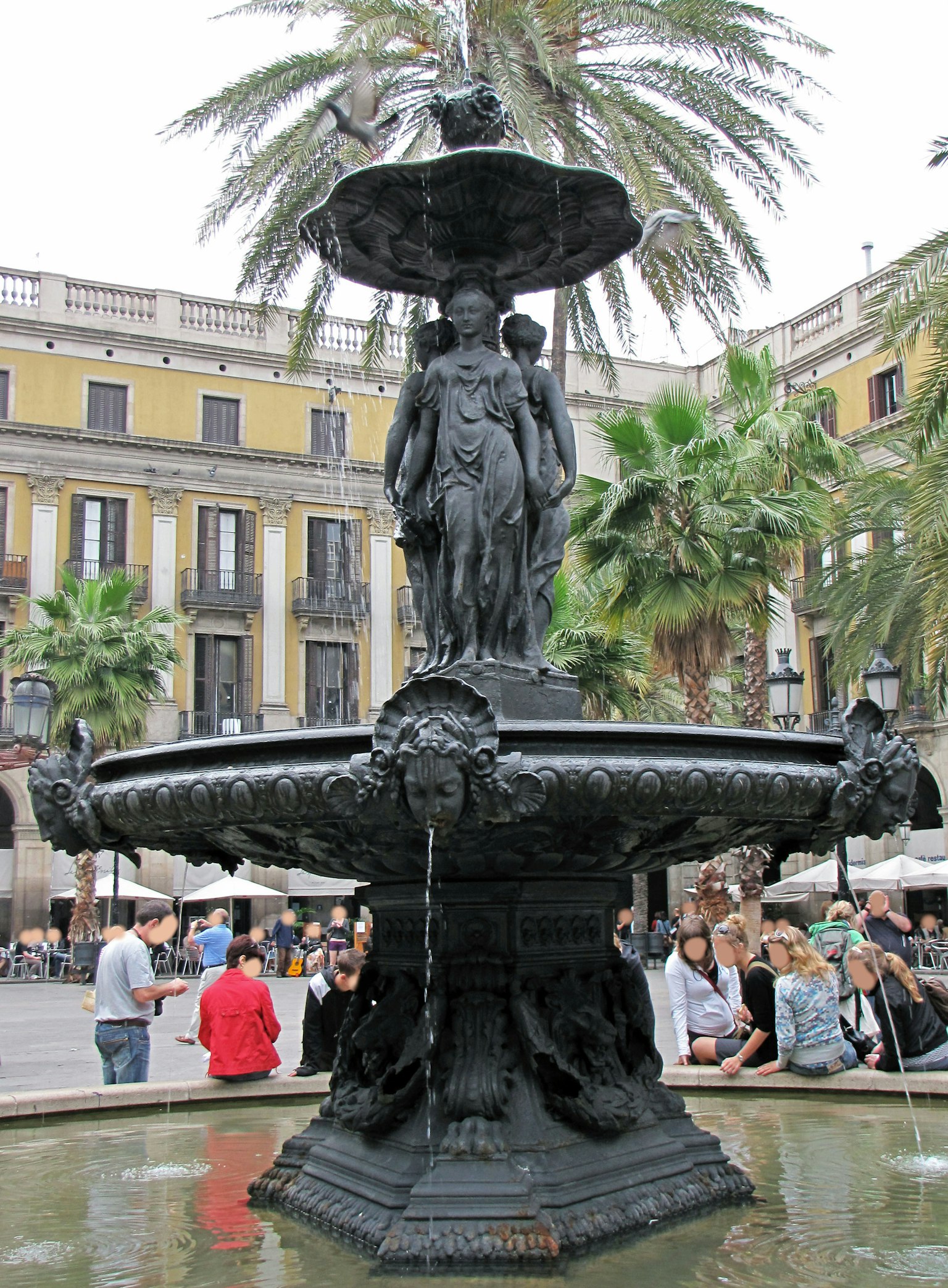 Belle fontaine noire dans une place à Barcelone avec des personnes autour