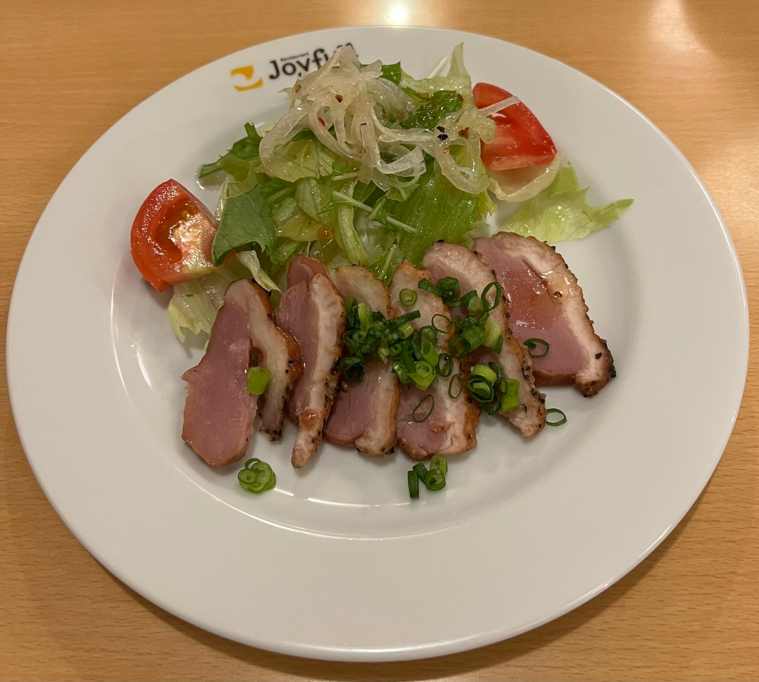 Irisan ayam disajikan dengan salad segar di piring putih
