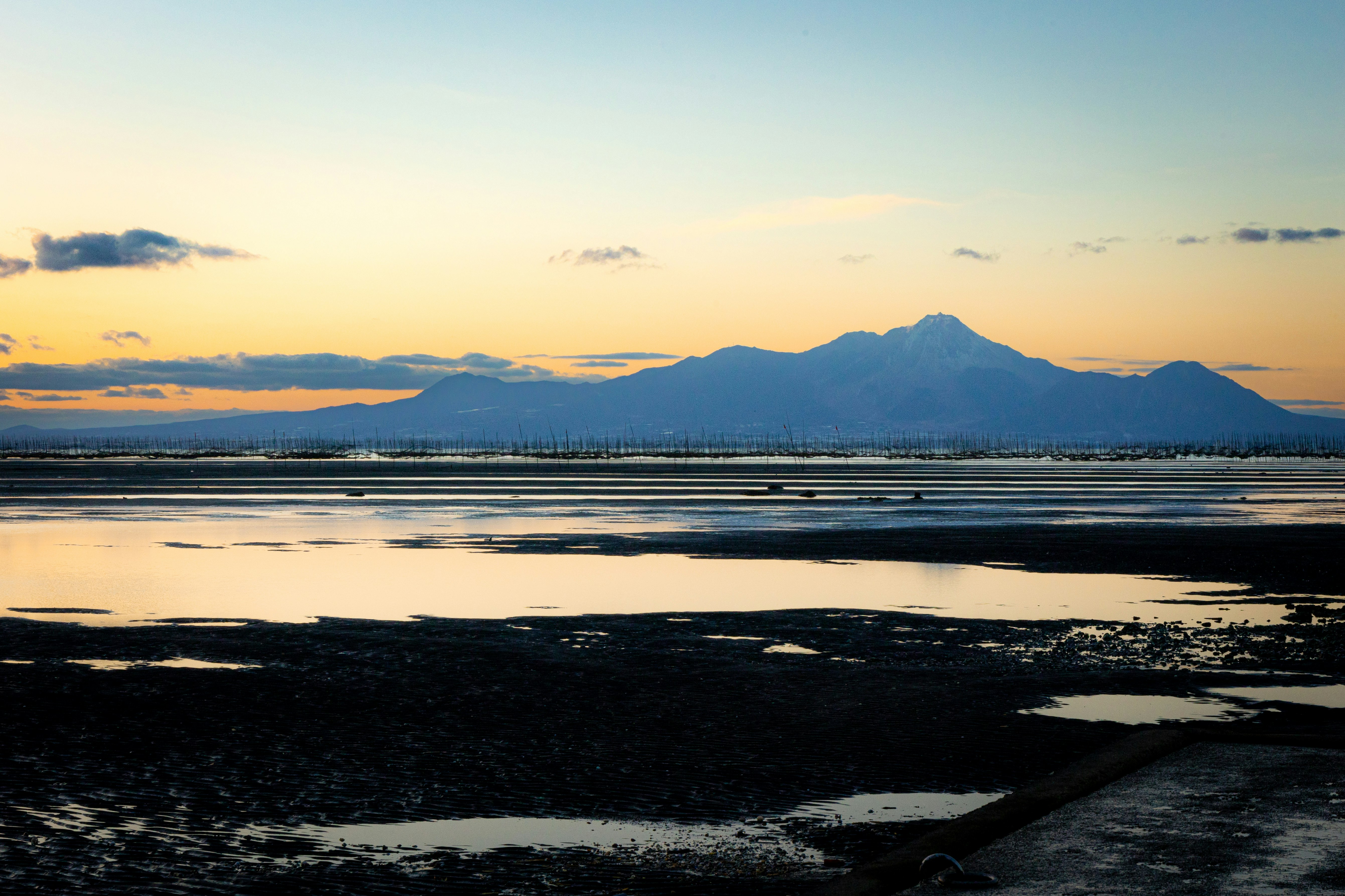 夕暮れの海辺と遠くの山並み