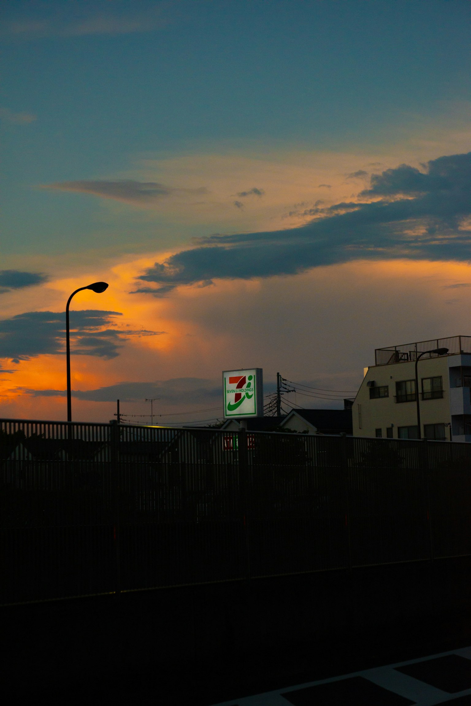 Un cielo al tramonto con lampione e insegna di un negozio