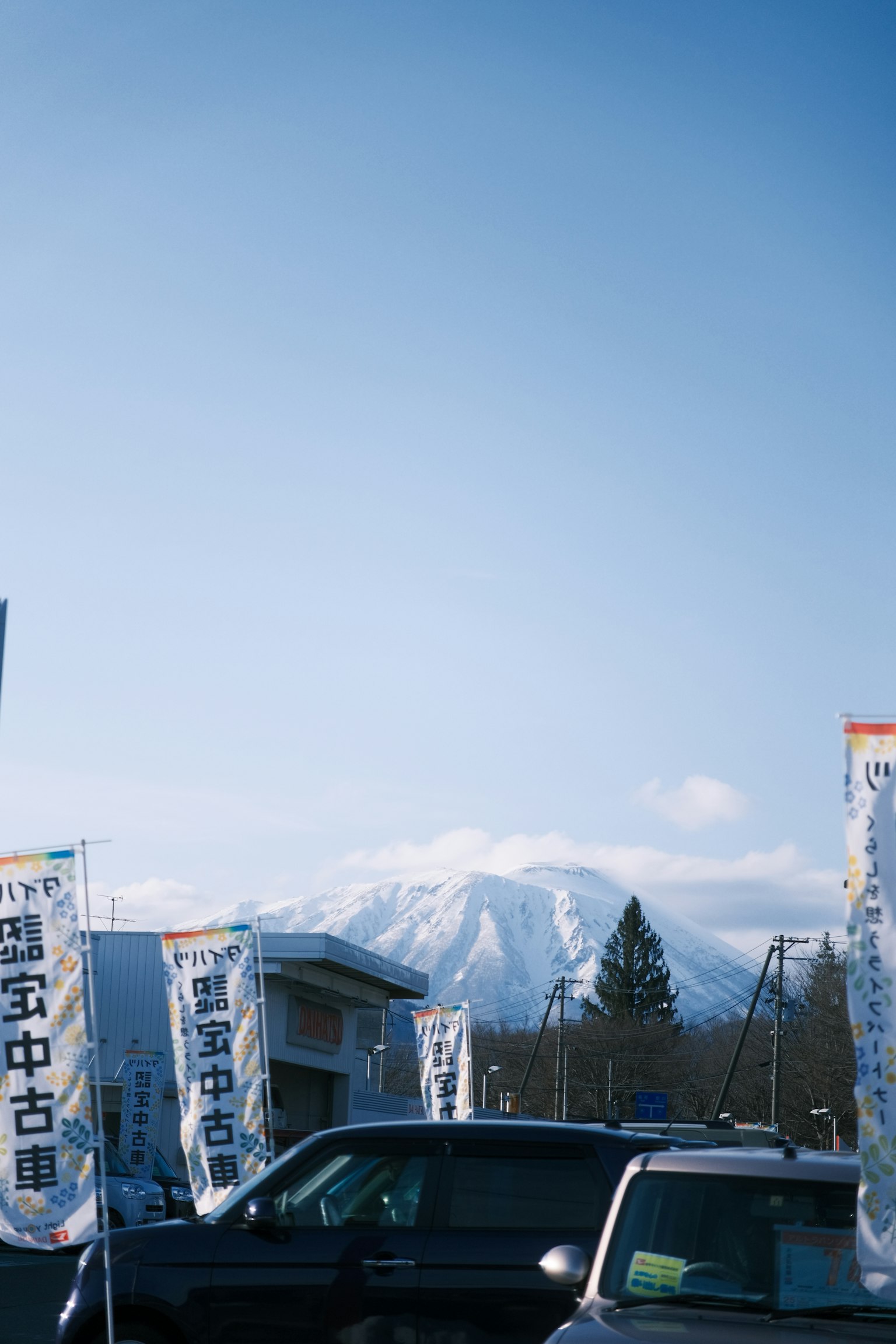 Mont enneigé sous un ciel bleu avec des voitures et des banderoles au premier plan