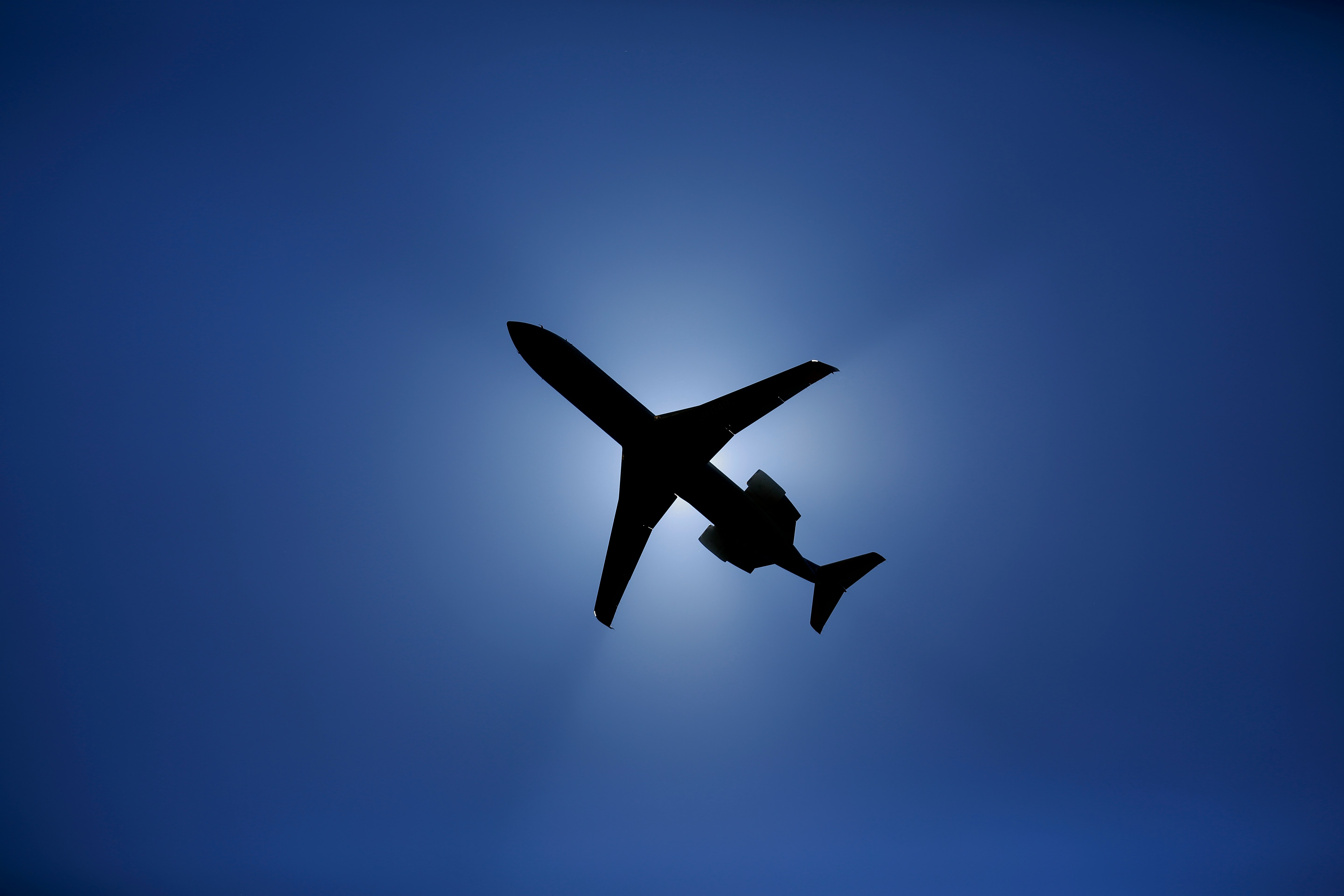青い空に浮かぶ飛行機のシルエット