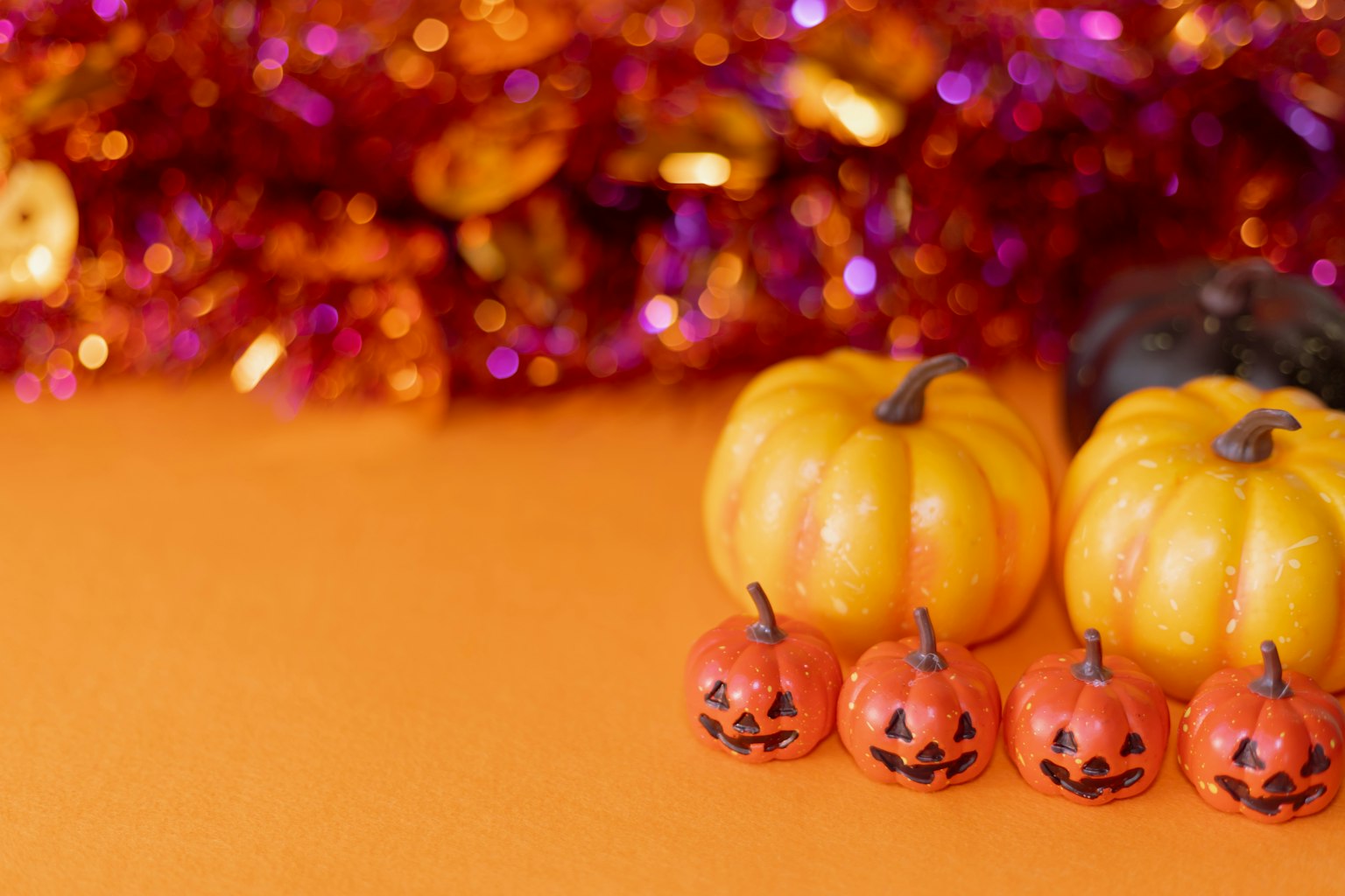 Dekorasi Halloween dengan labu kuning dan jack-o'-lantern oranye di latar belakang oranye