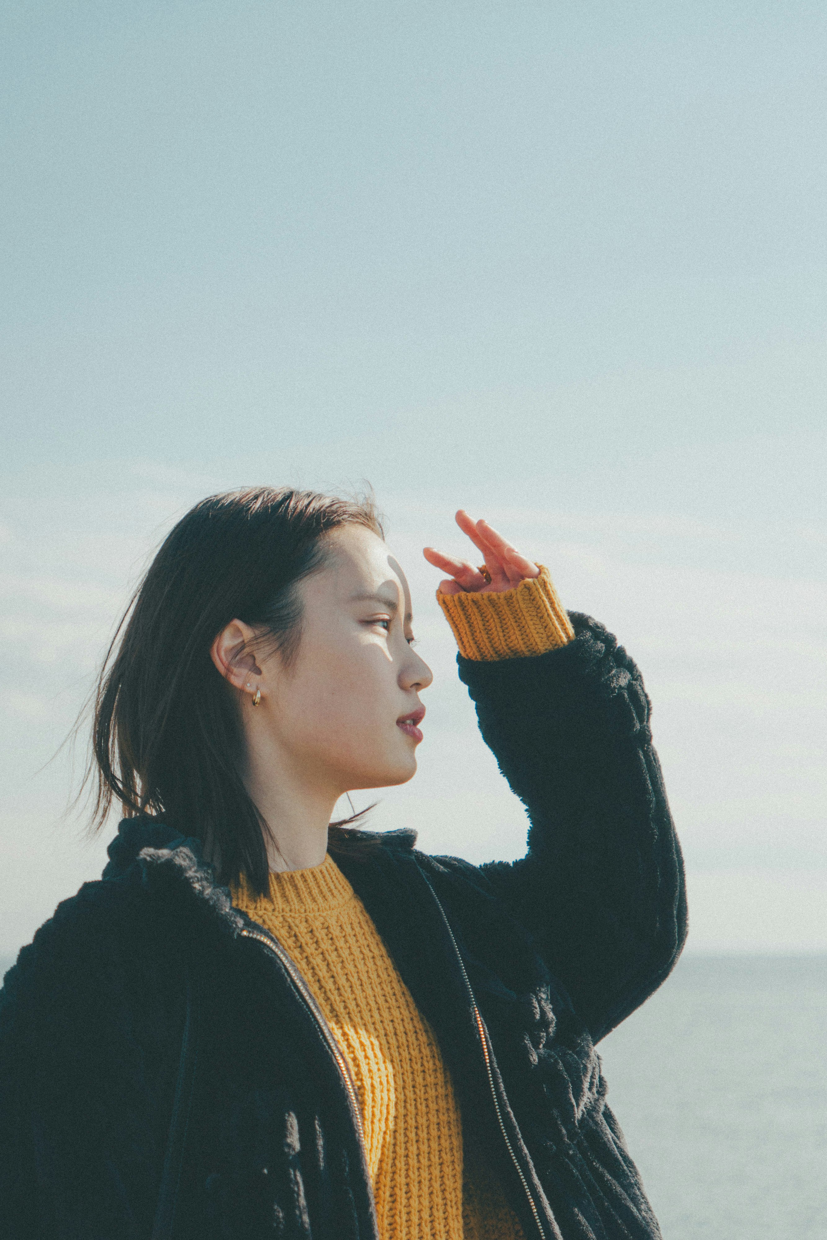 海辺を見上げる手を上げた女性