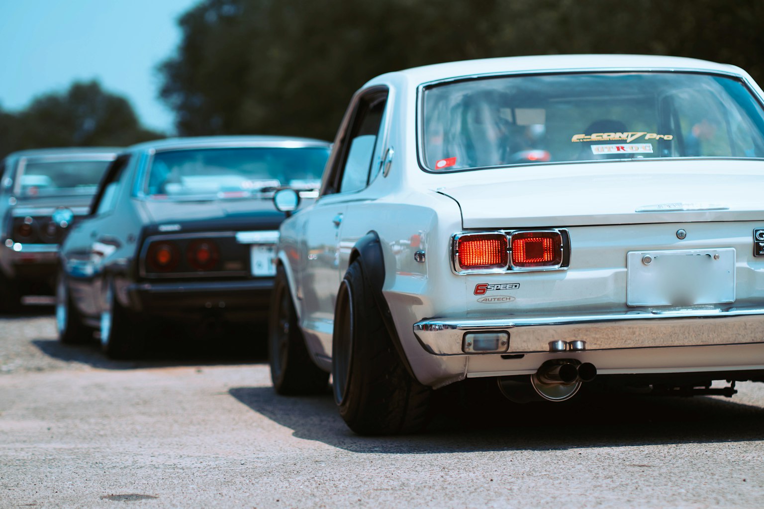 Klassisches weißes Auto und schwarzes Sportauto, die auf einer Straße aufgereiht sind