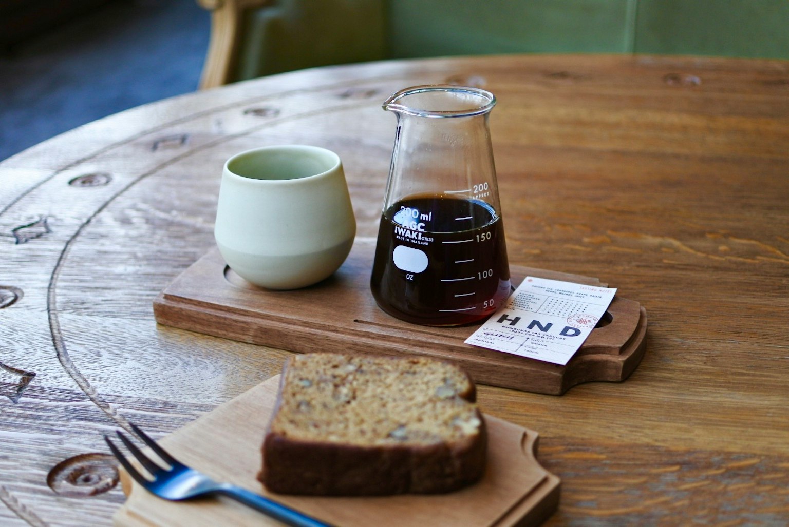 Scene with coffee, a green cup, and bread on a wooden table