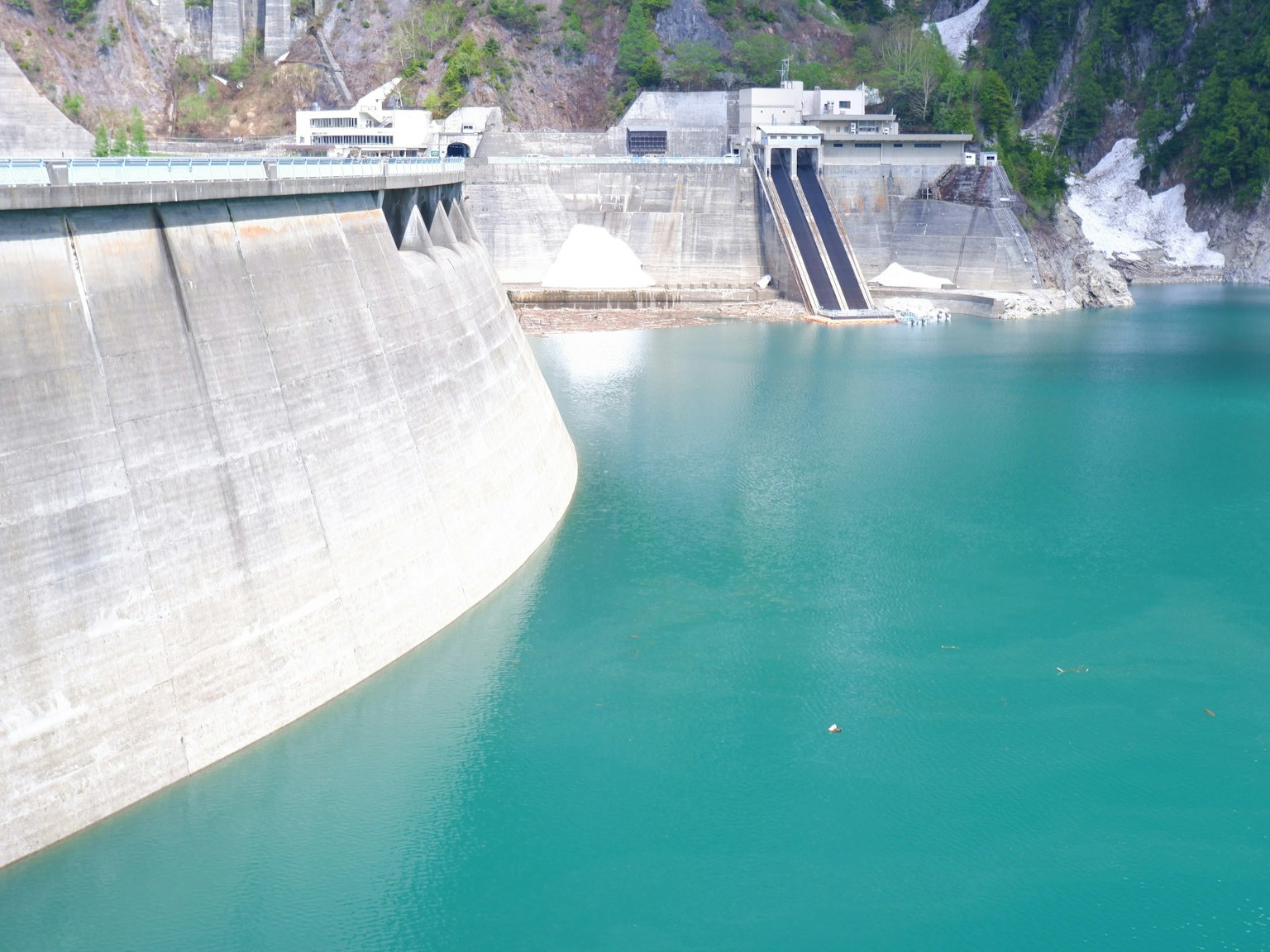Diga con acqua turchese muro di cemento e montagne verdi