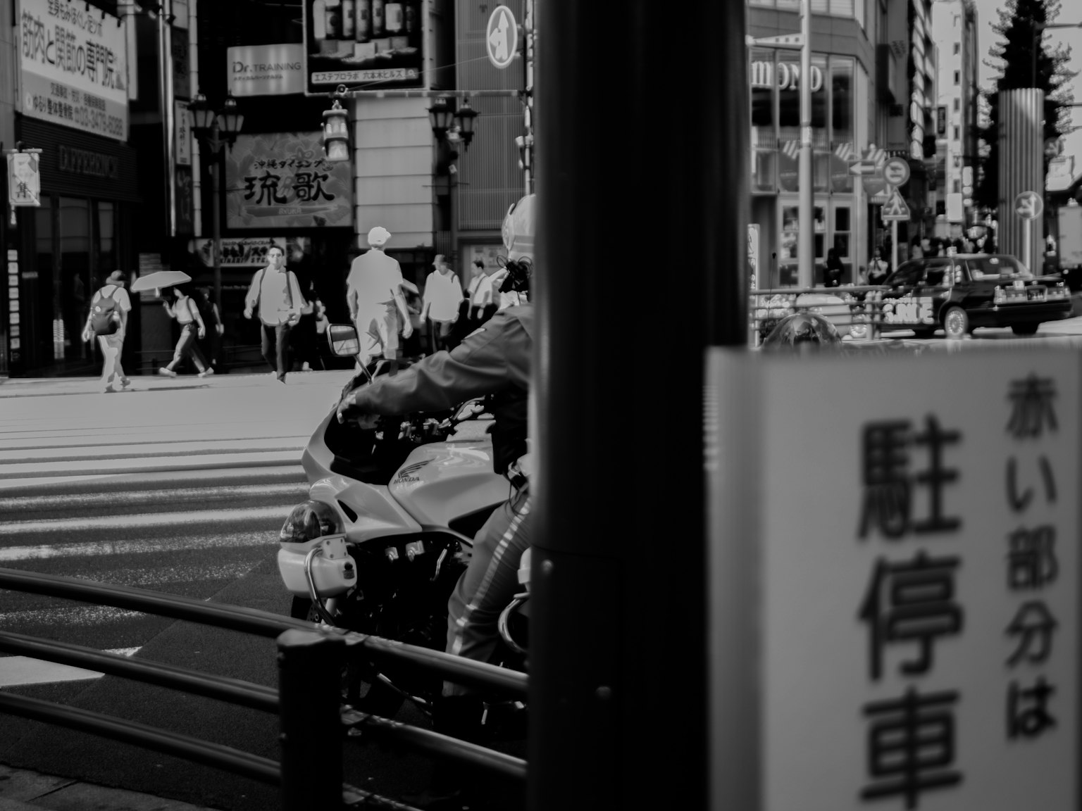 Escena urbana en blanco y negro con una motocicleta esperando en un semáforo y peatones
