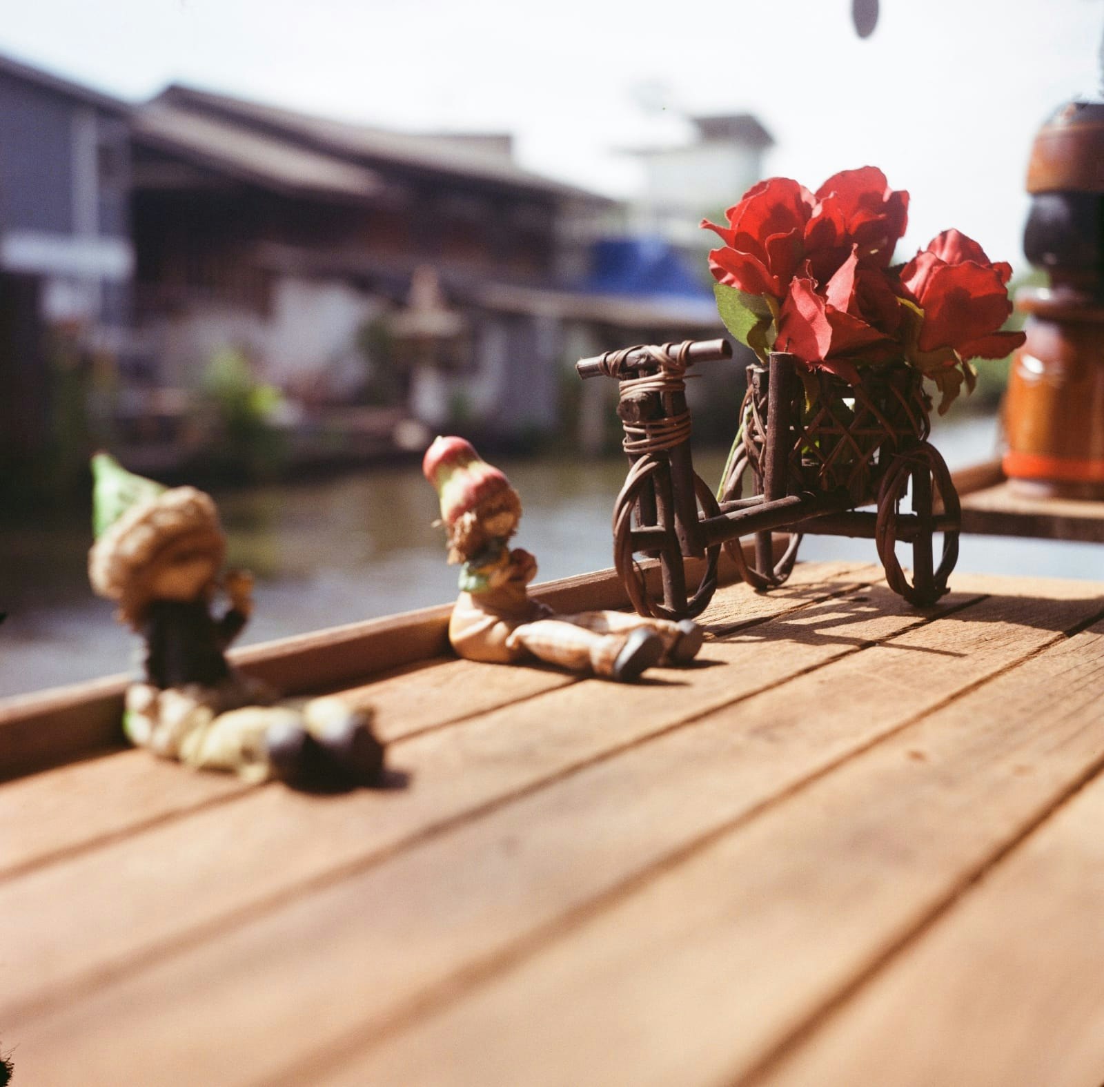 バラの花を載せた自転車と木製のベンチのある路地
