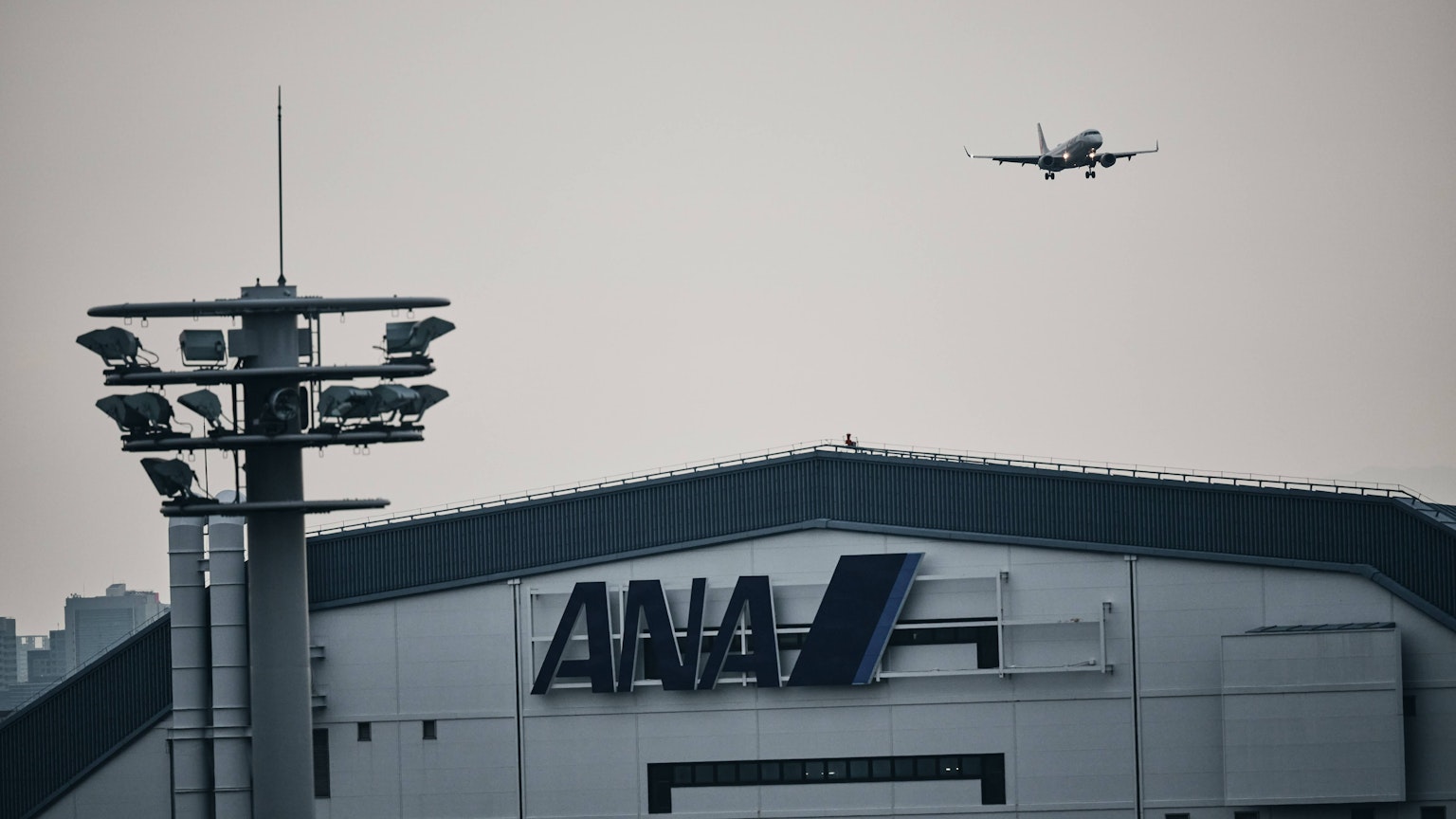 ANA 로고가 보이는 공항 건물과 접근하는 비행기