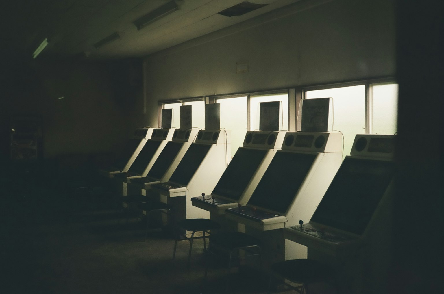 薄暗い部屋に並ぶ古いゲーム機の列