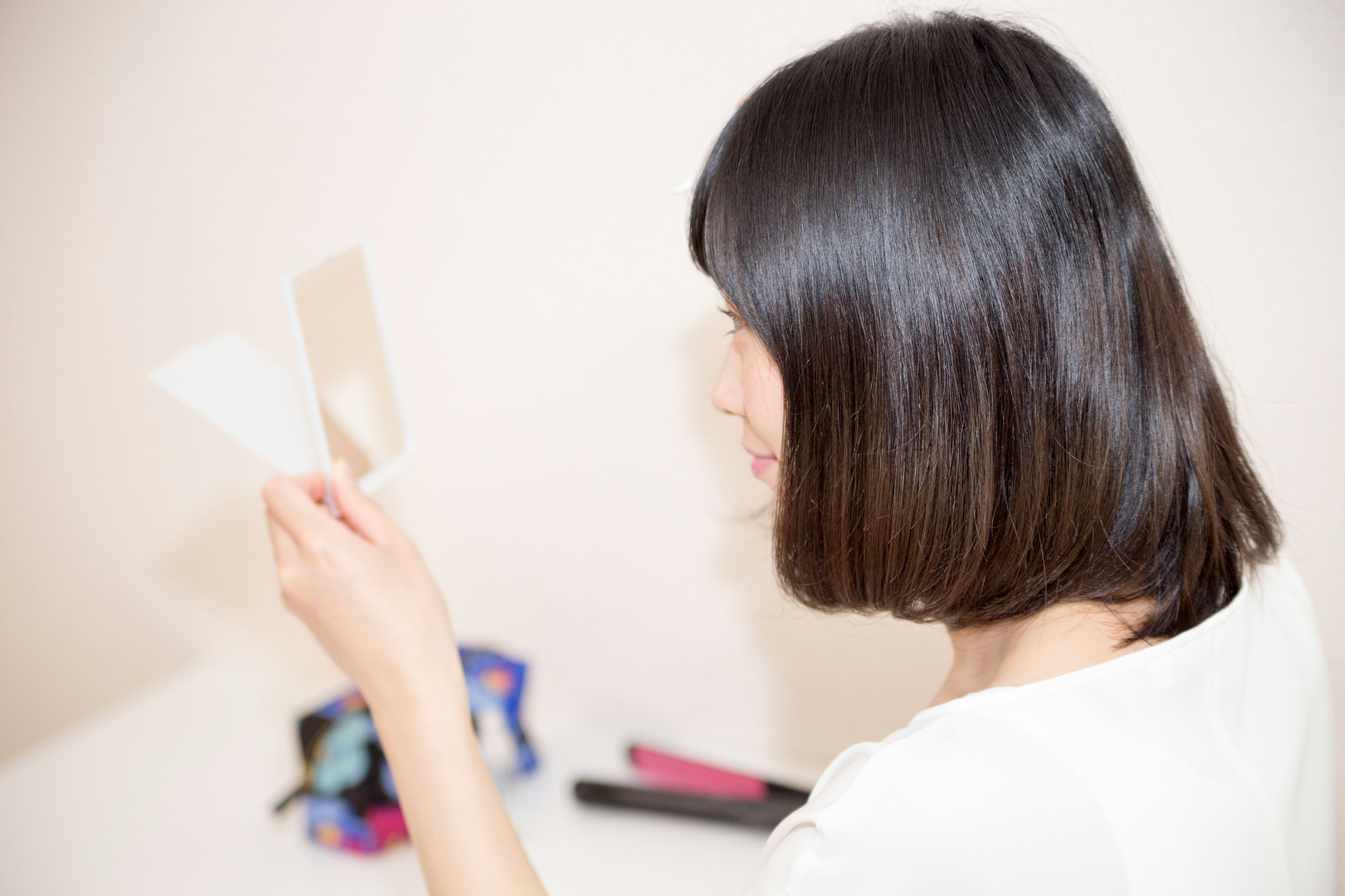 白い壁の前でメイク道具を手にする女性