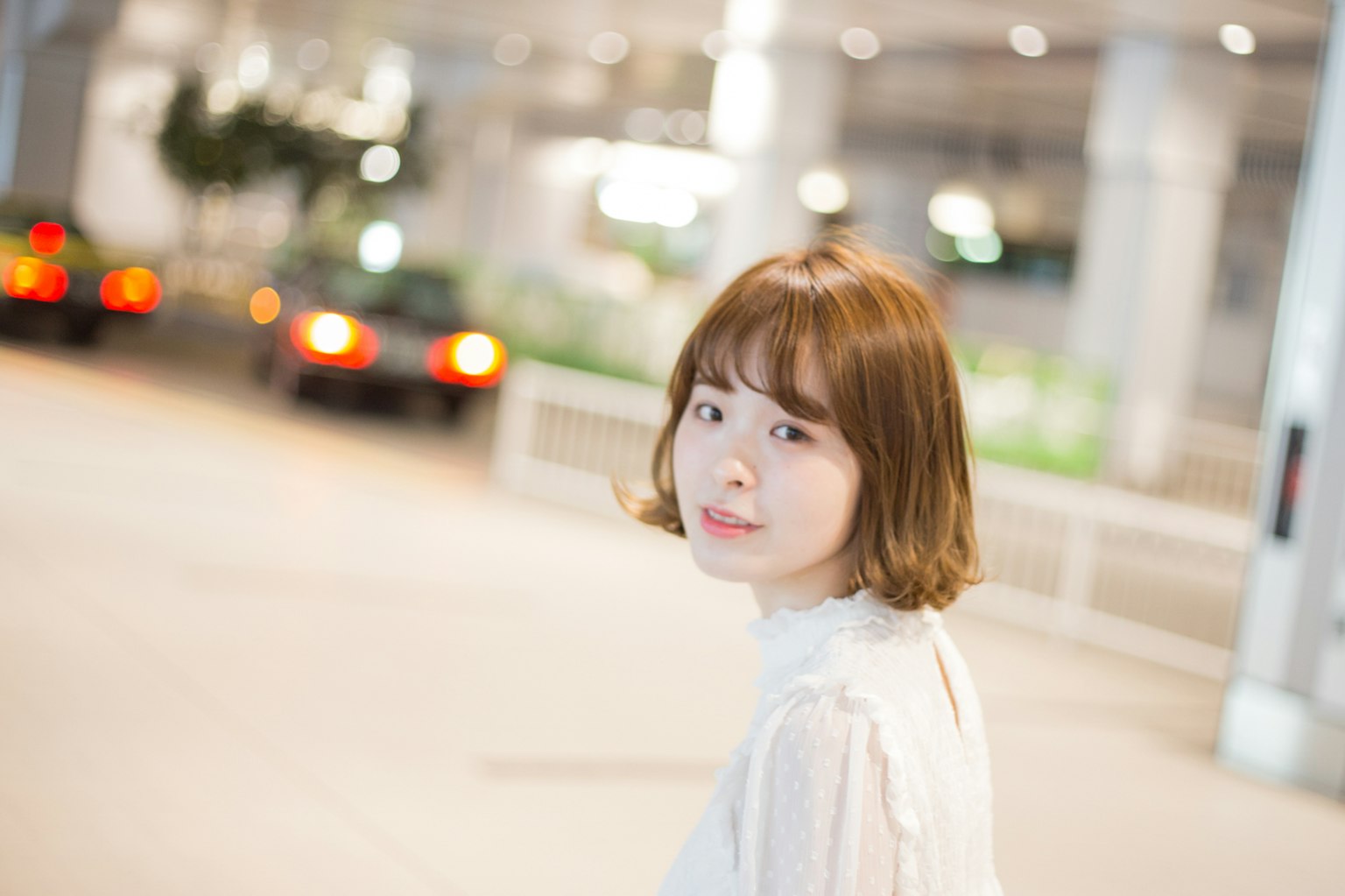 Junge Frau schaut zurück mit verschwommenem Stadt Hintergrund