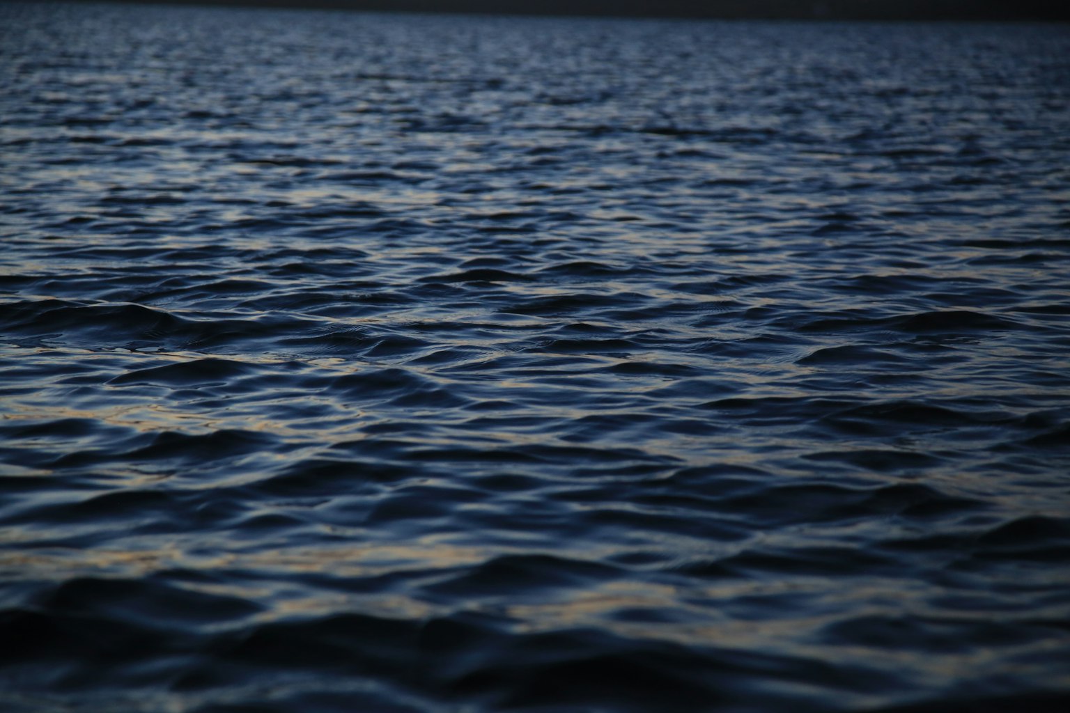 Ruhige Wasseroberfläche mit Wellen in tiefblauen Tönen