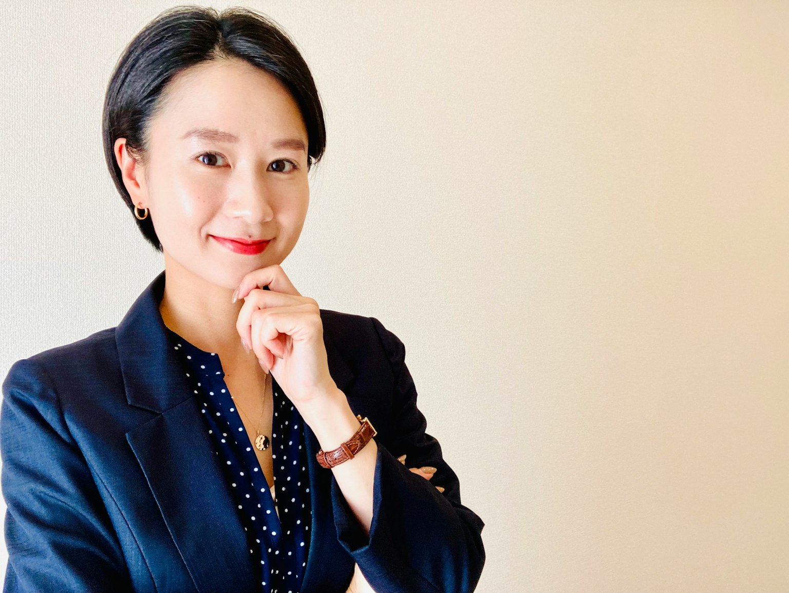 Eine Frau in einem Businessanzug, die nachdenklich lächelt und ihre Hand am Kinn hat