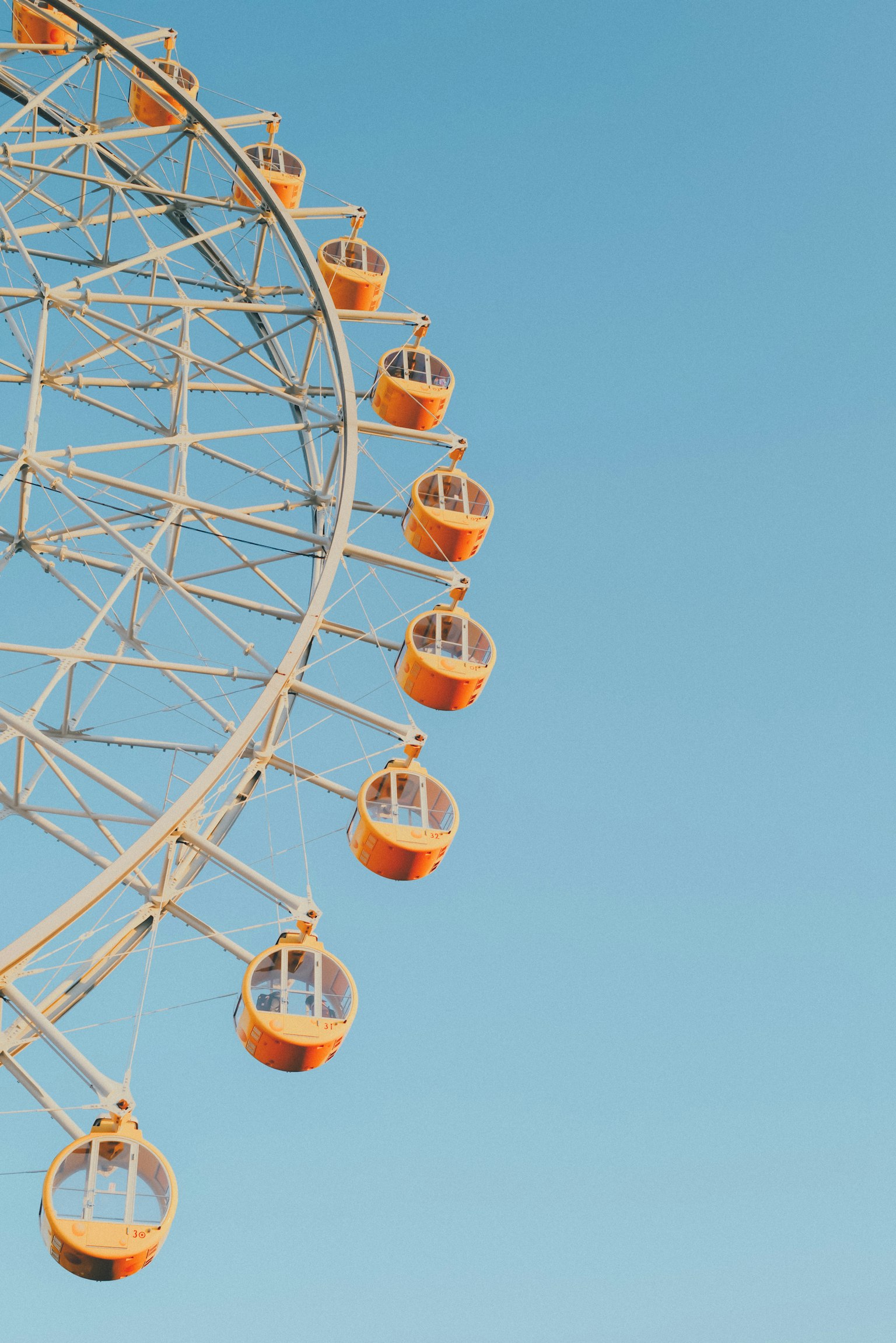 Orange Ferris wheel capsules against a blue sky