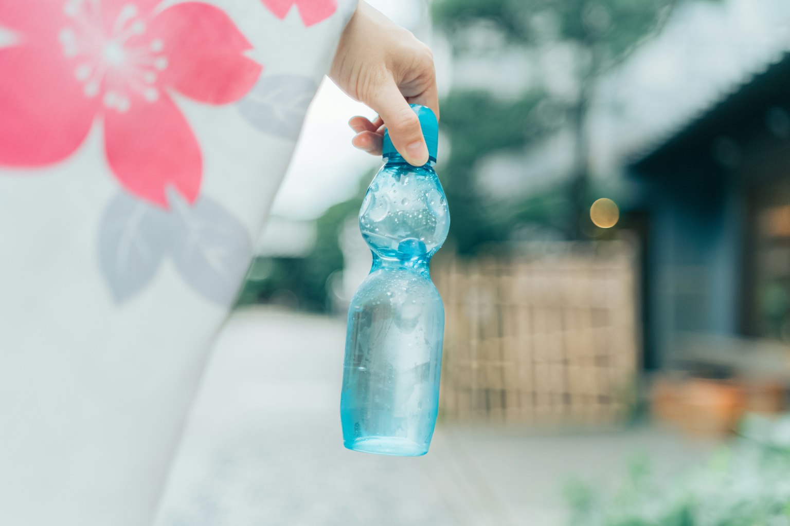 A hand in a kimono holding a blue bottle