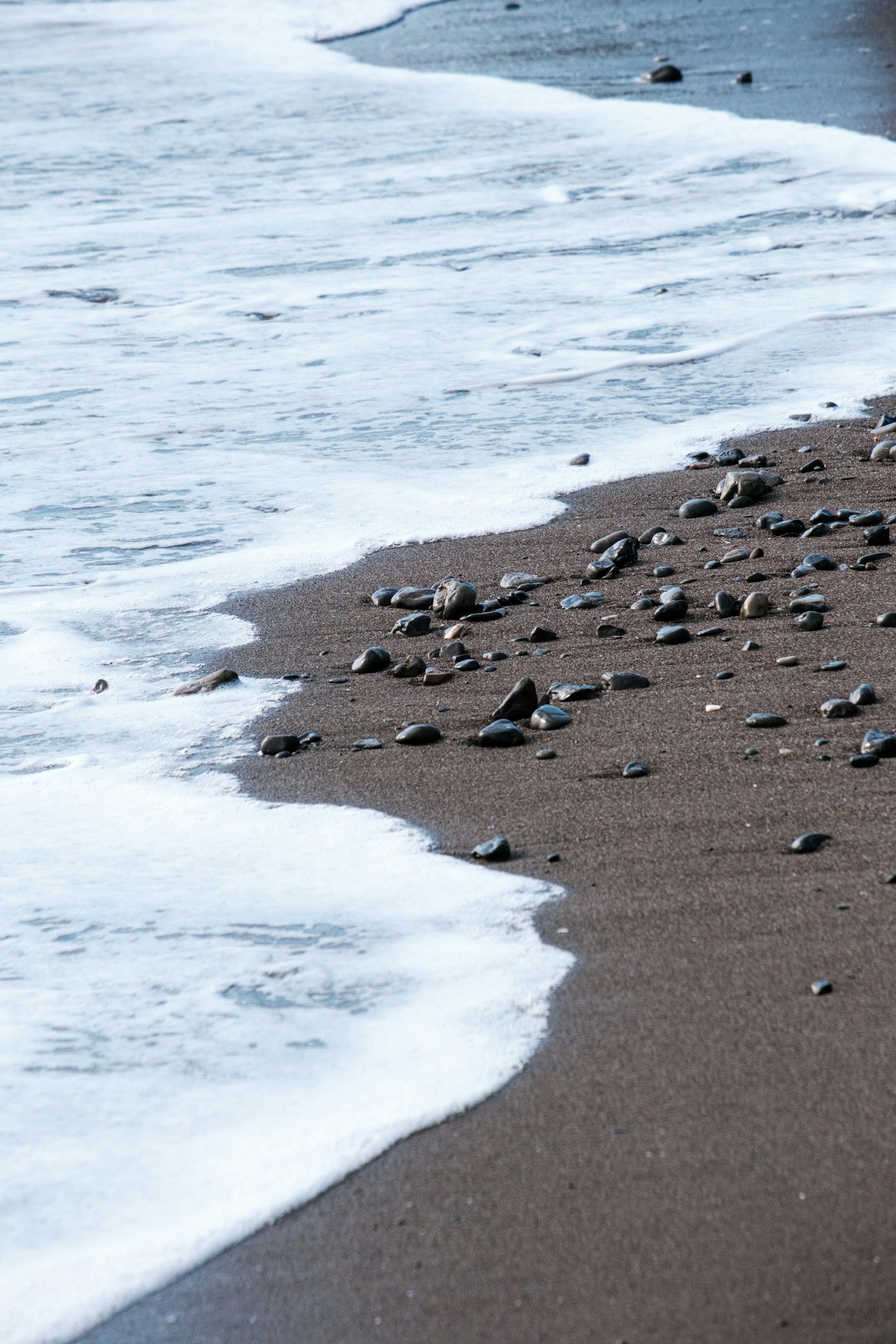 Waves crashing on a sandy beach with pebbles