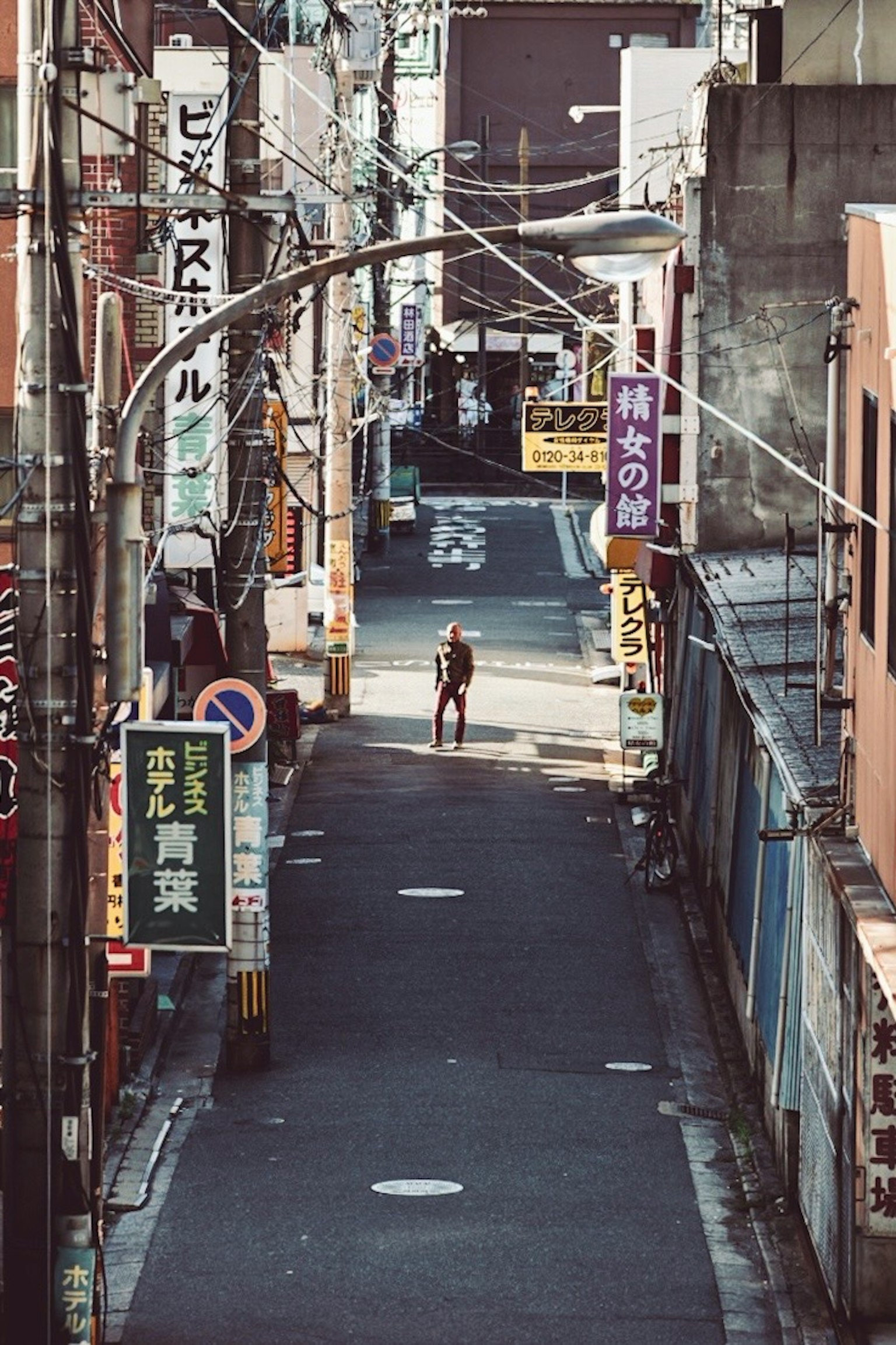 狭い通りに立つ人と看板が並ぶ風景