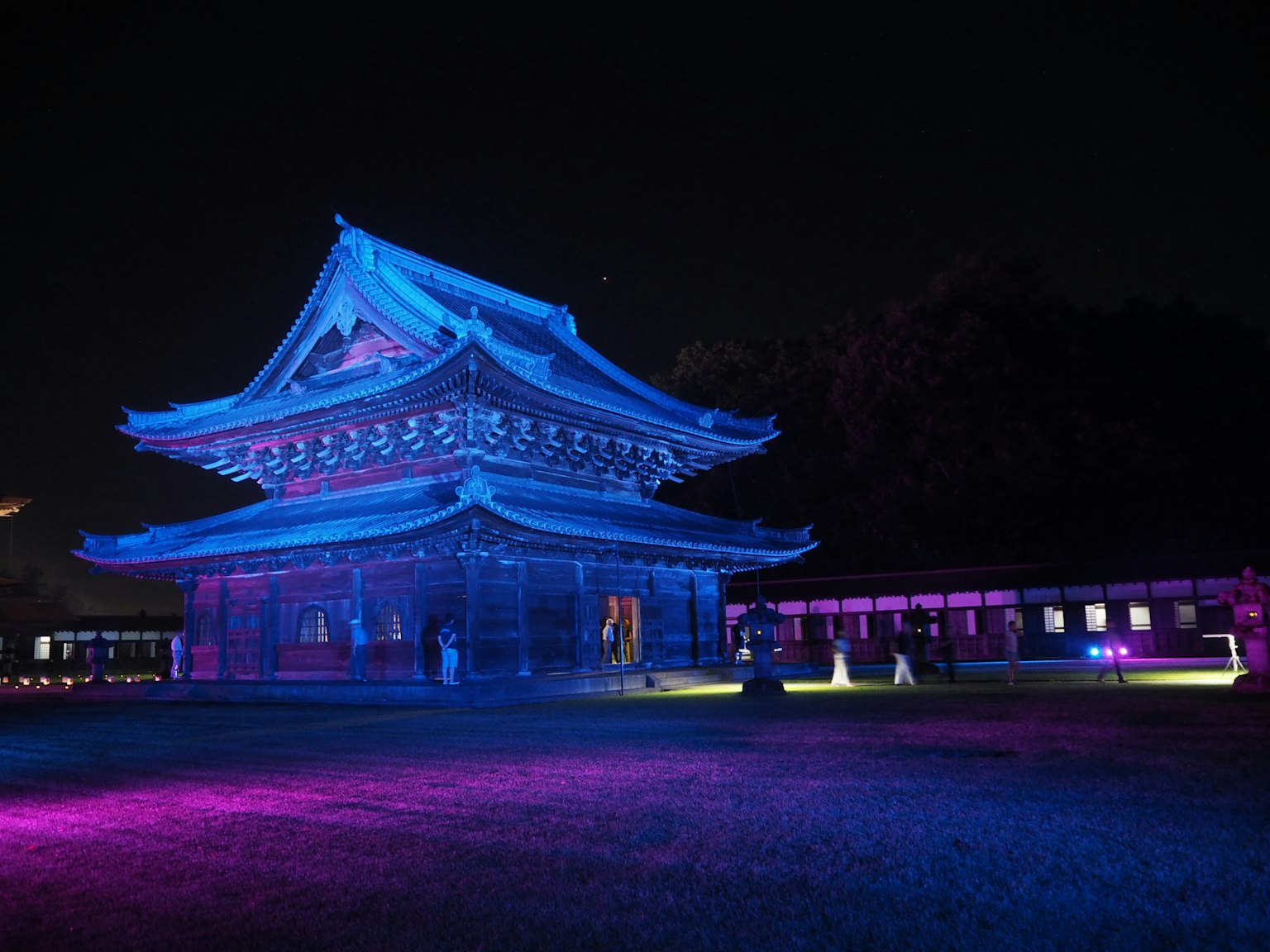 Traditionelles Gebäude bei Nacht in blauem Licht beleuchtet mit der umgebenden Landschaft