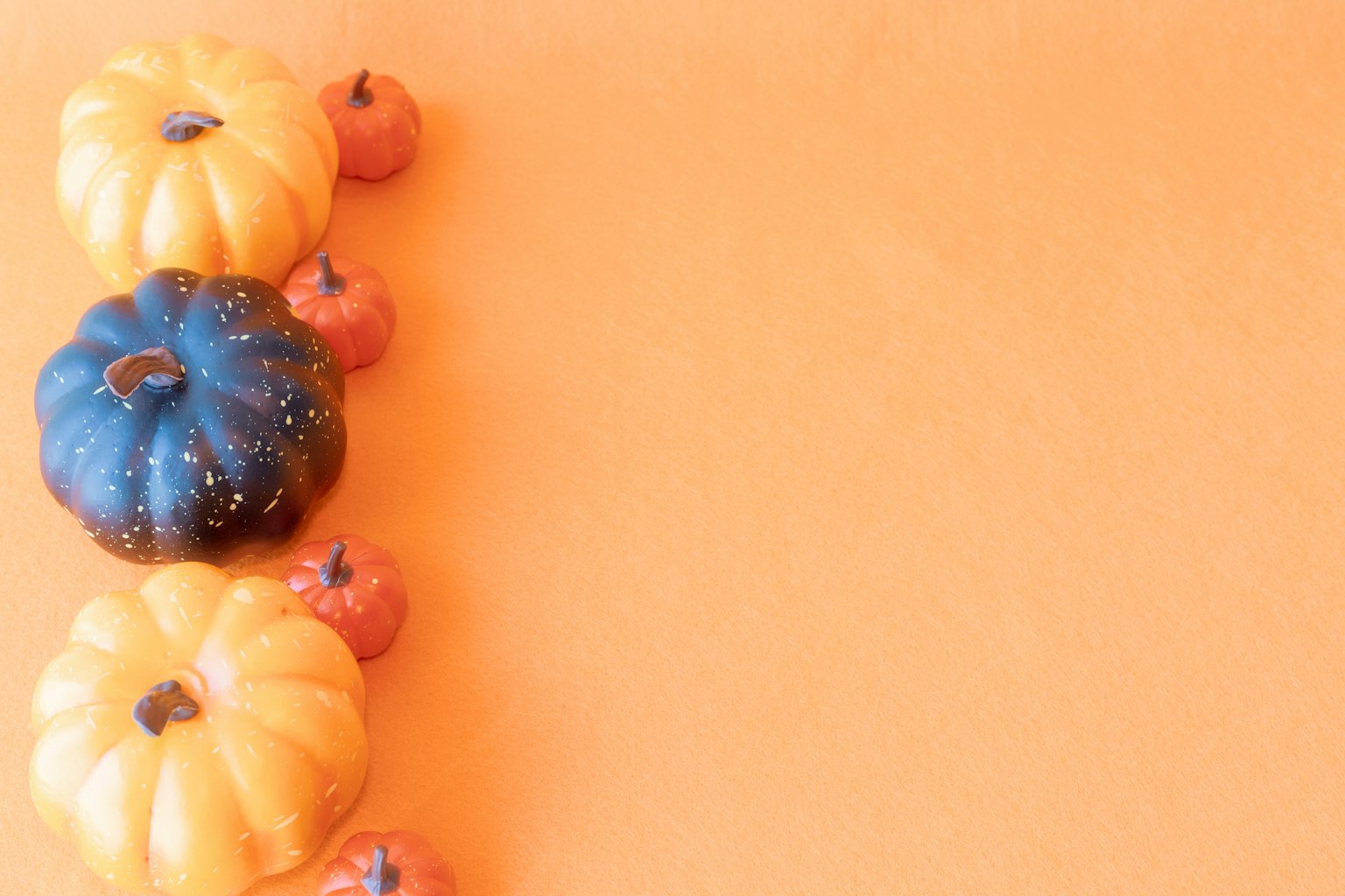 Colorful pumpkins arranged on an orange background