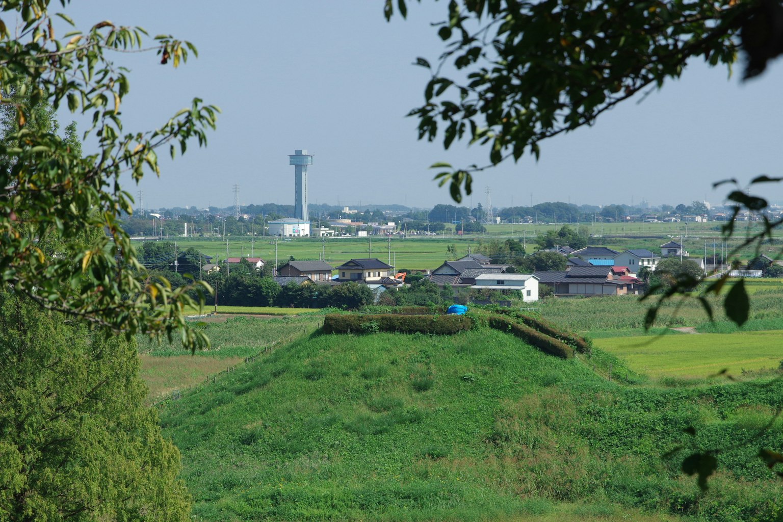Una piccola collina circondata da verde con edifici in lontananza