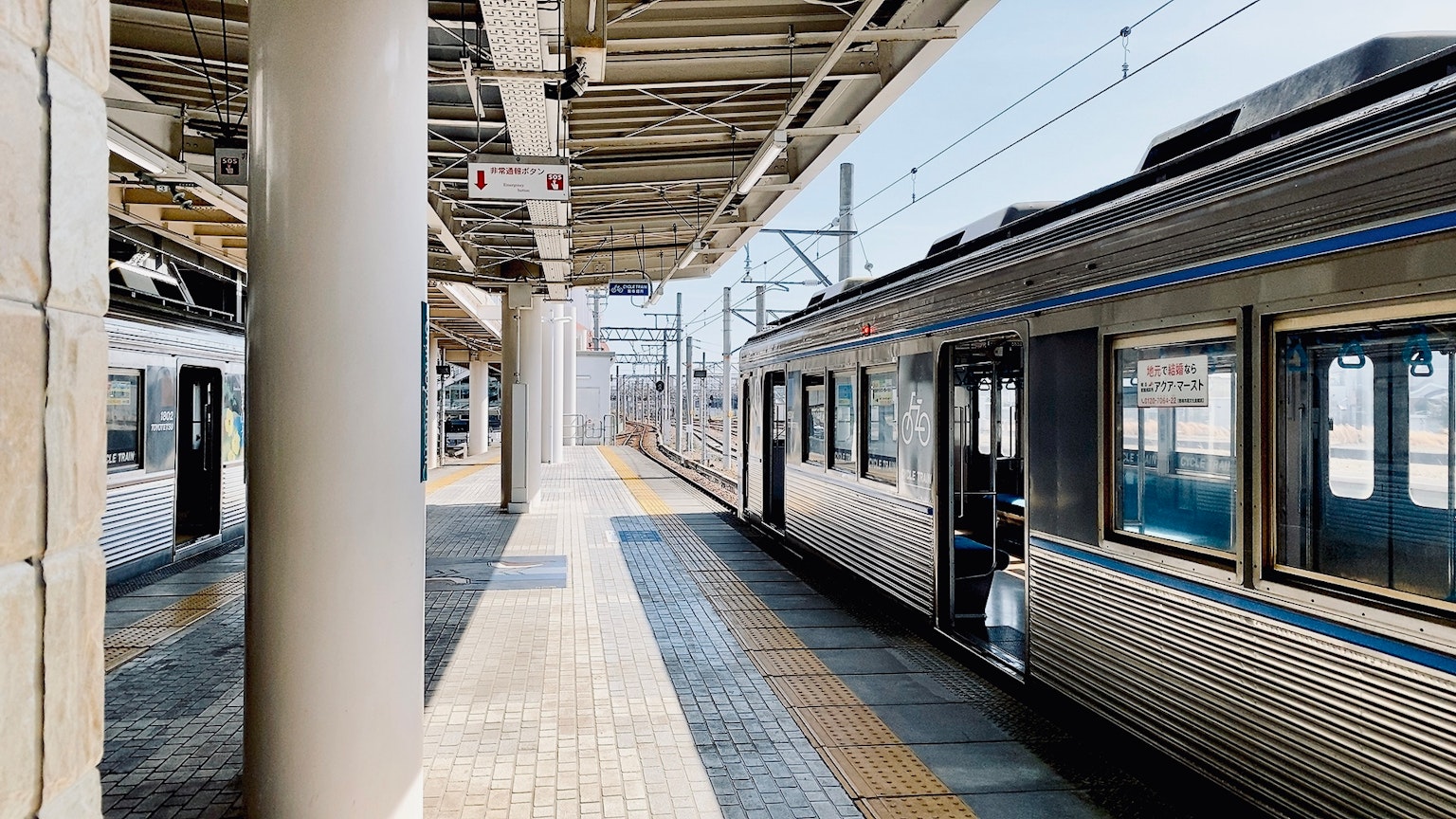 แพลตฟอร์มสถานีรถไฟที่สว่างพร้อมรถไฟจอดและเสา