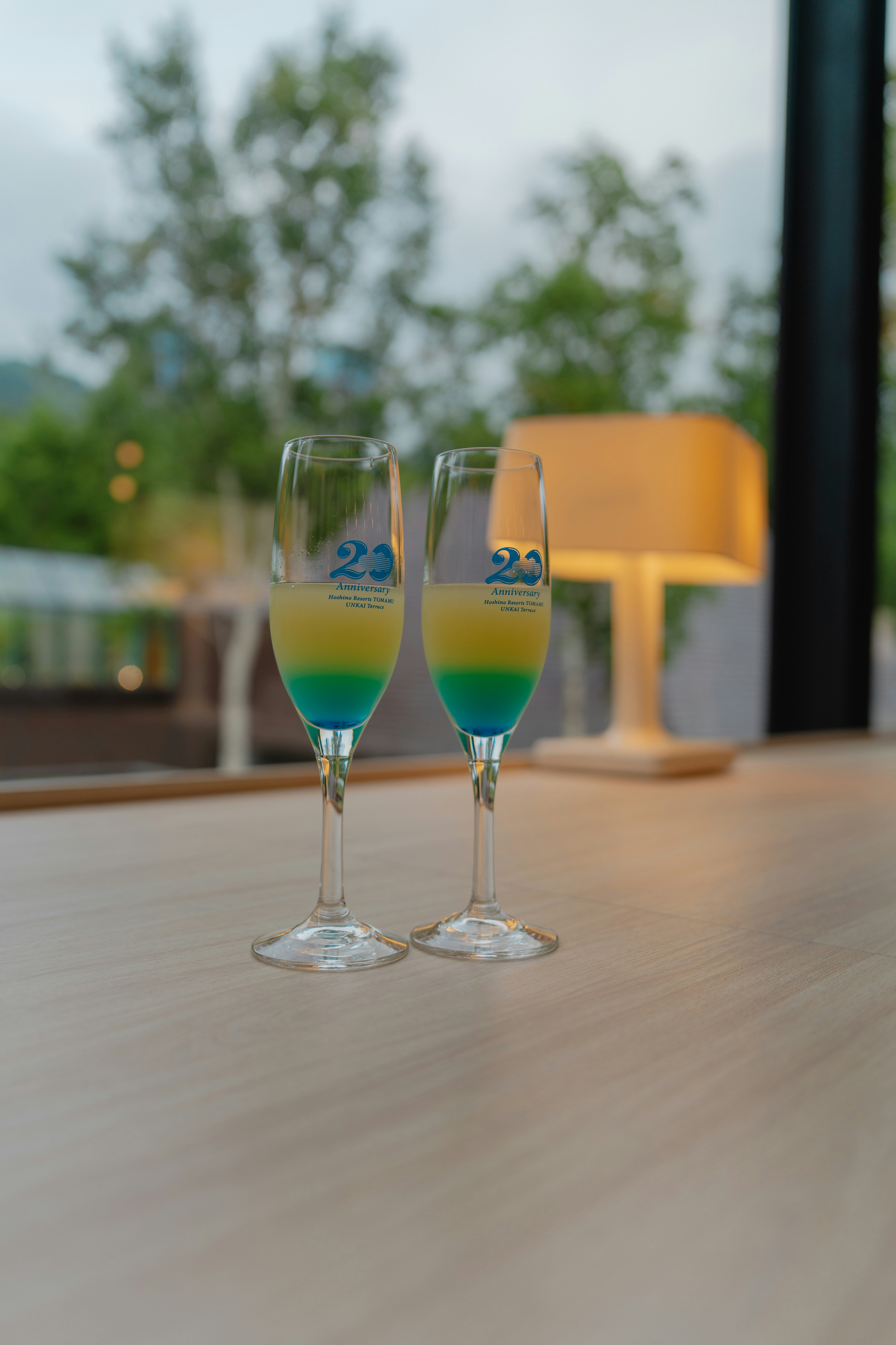 Two champagne glasses on a wooden table on a terrace