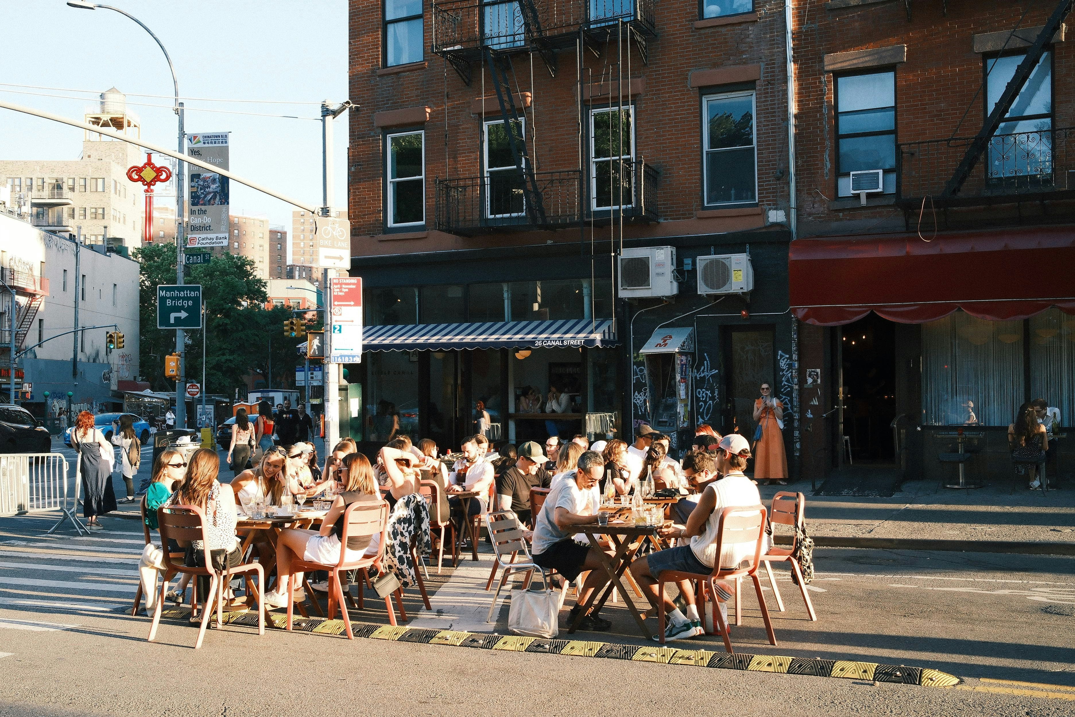 Menschen essen und plaudern an provisorischen Straßentischen an einer Straßenecke