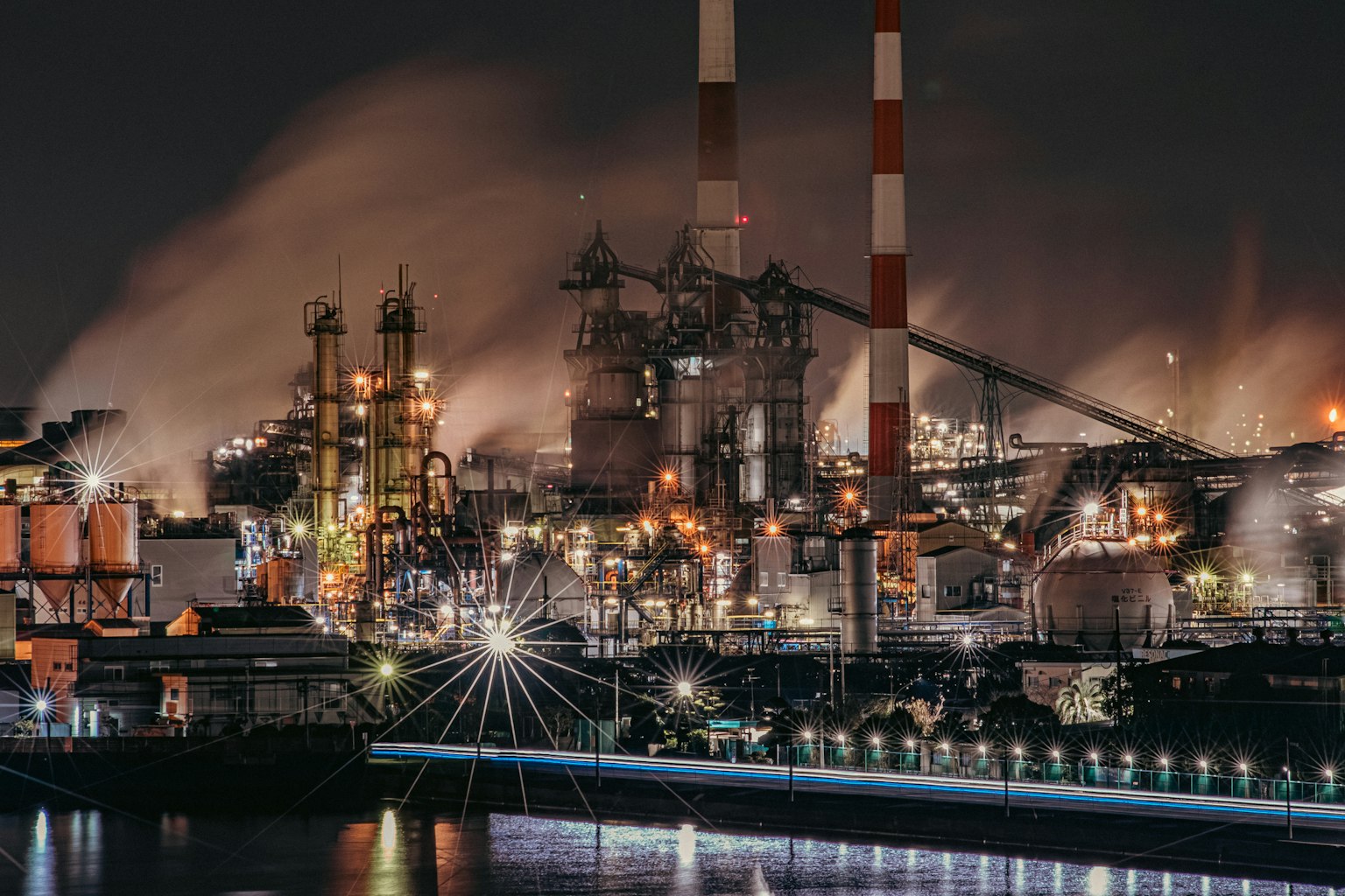 Paysage industriel nocturne avec des cheminées et des usines illuminées