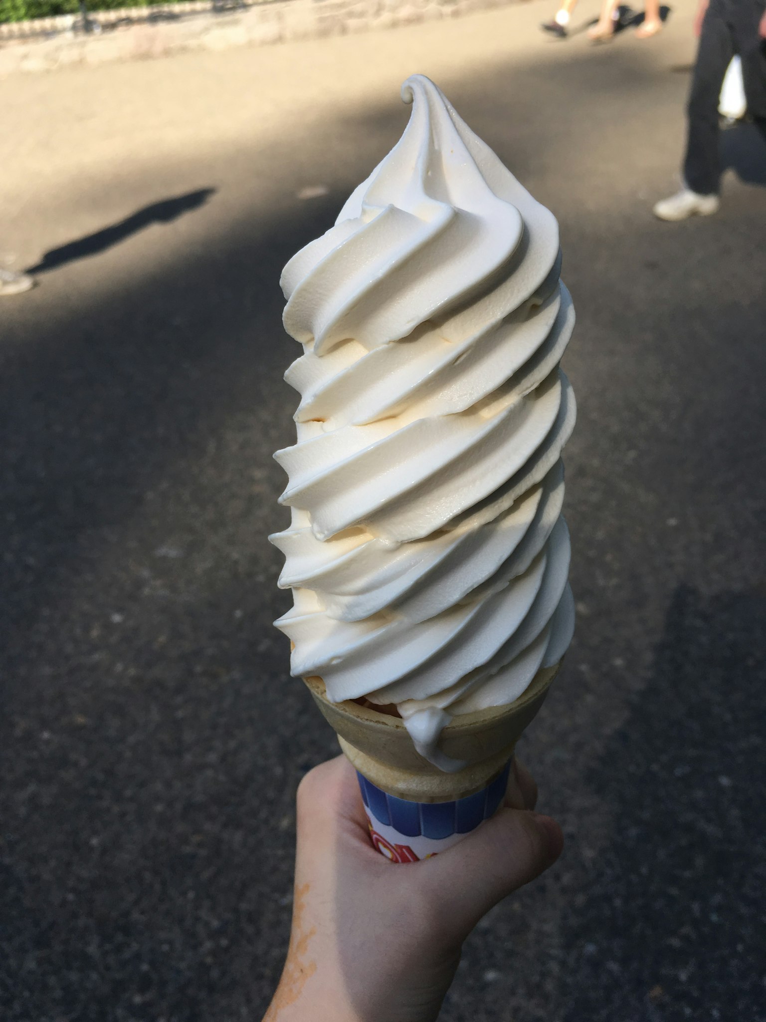 Sebuah tangan memegang es krim lembut besar dalam kerucut
