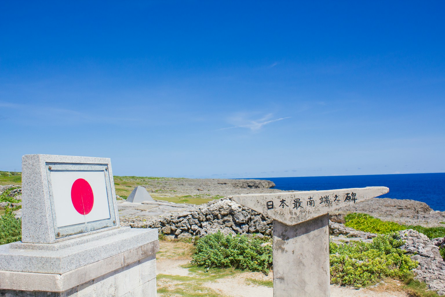 Señal con la bandera japonesa contra un cielo azul y el océano