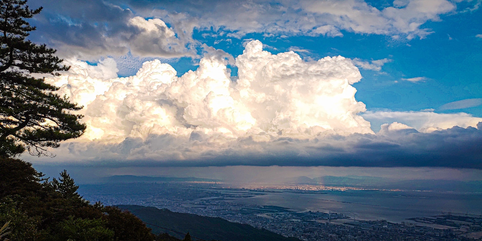 View of white clouds under blue sky with ocean in the background