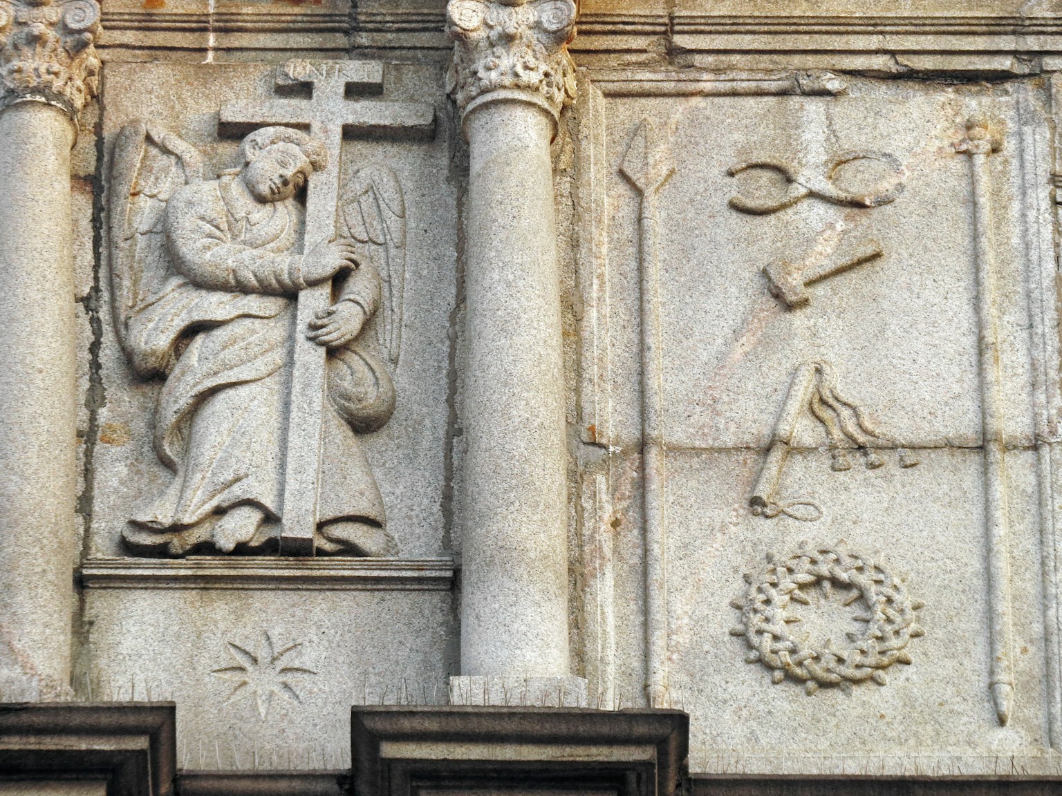 Angelo scolpito in pietra che tiene una croce su un'opera murale
