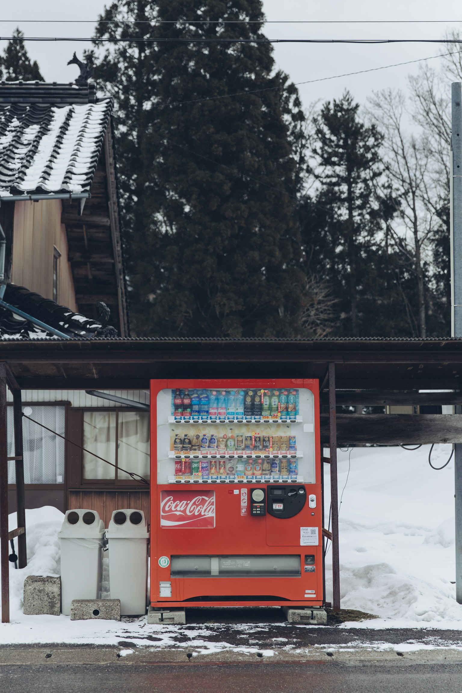 Un distributore automatico nella neve con bidoni bianchi nelle vicinanze