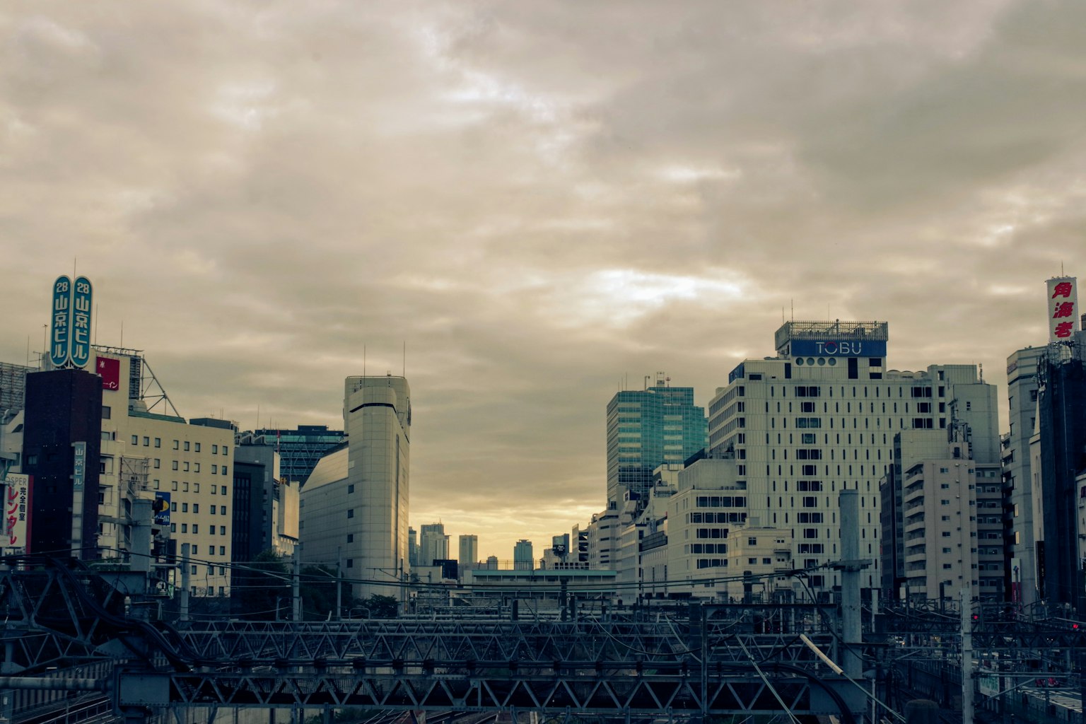 เส้นขอบฟ้าของเมืองพร้อมอาคารสูงและรถไฟใต้ท้องฟ้าที่มีเมฆมาก