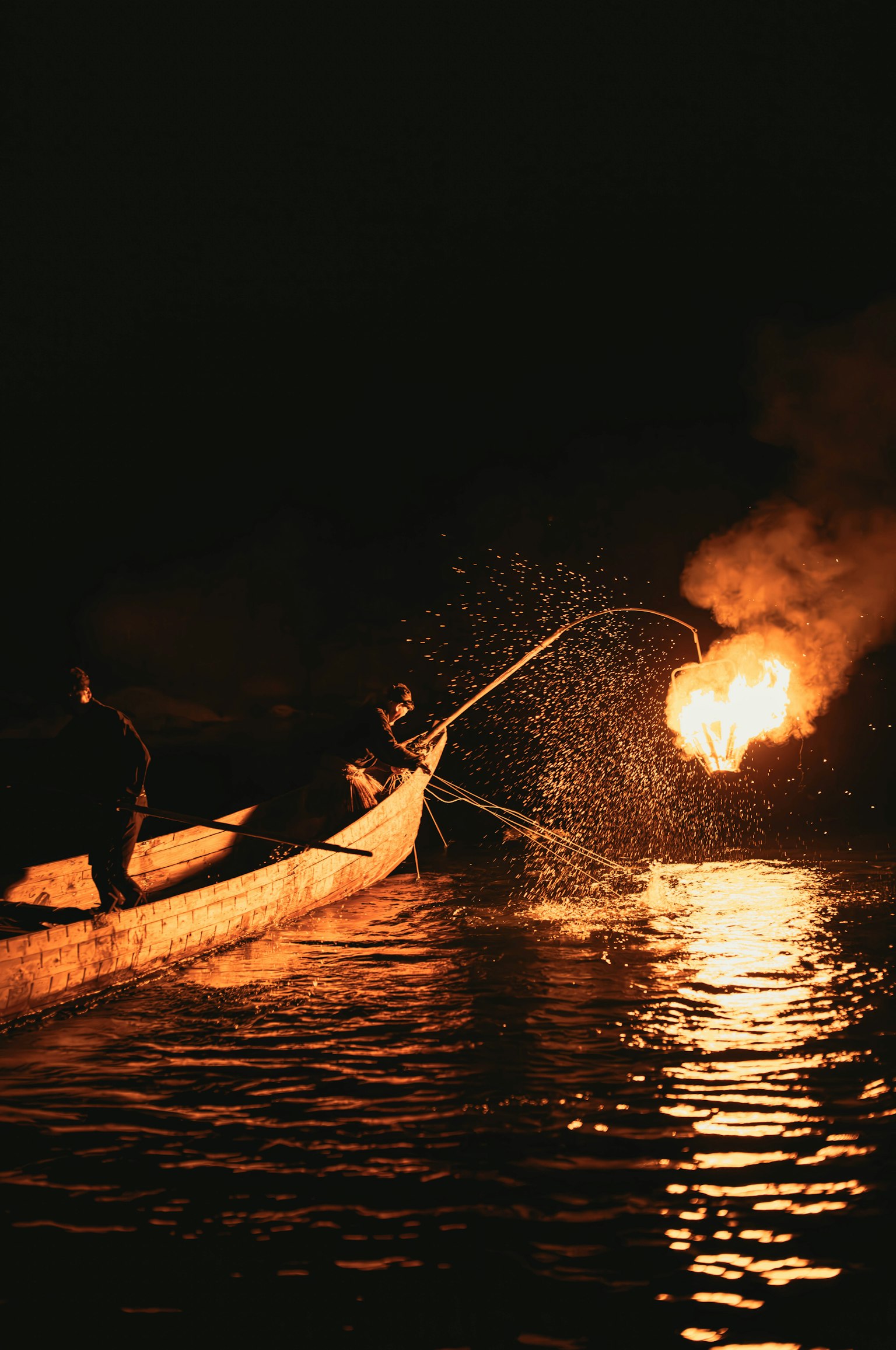 Pescatori in barca di notte con fiamme e spruzzi d'acqua