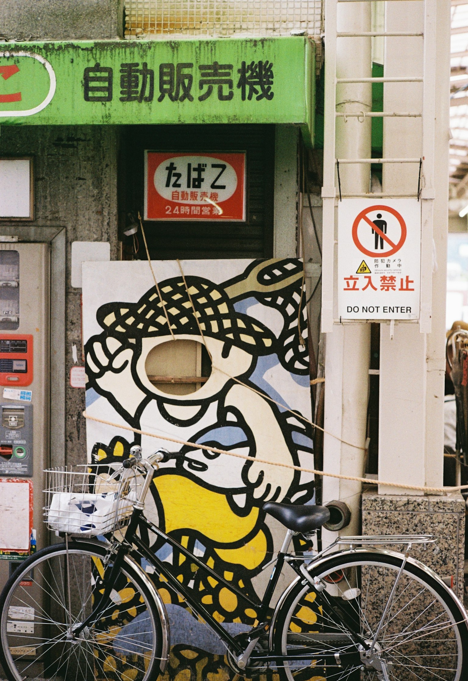 Una máquina expendedora con una ilustración de personaje y una bicicleta delante