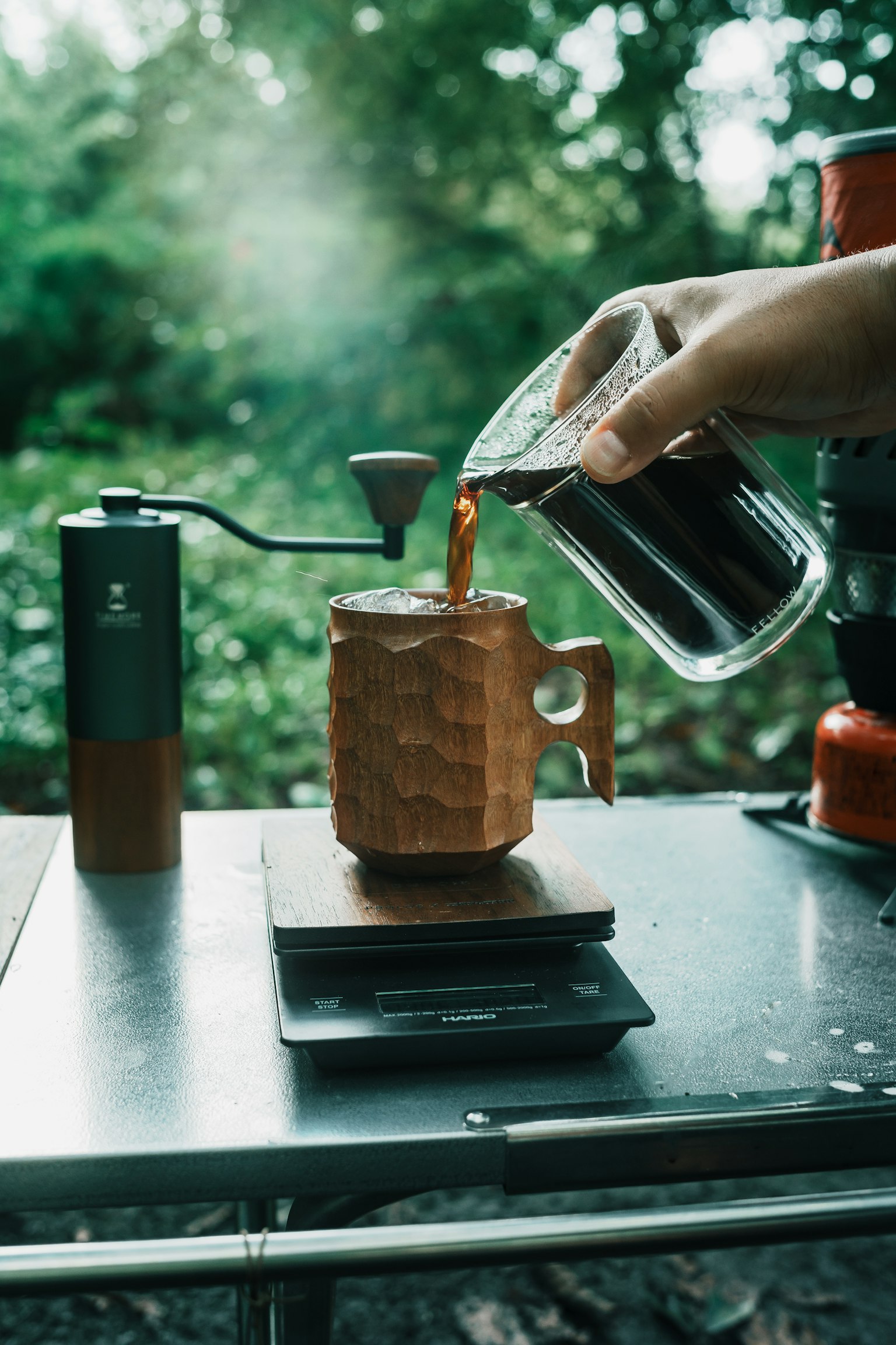 手のひらでコーヒーを注いでいる画像 立体的なカップとコーヒーグラインダーが見える