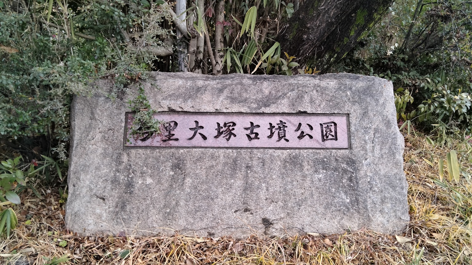 Monumento de piedra que muestra el nombre de un parque rodeado de naturaleza