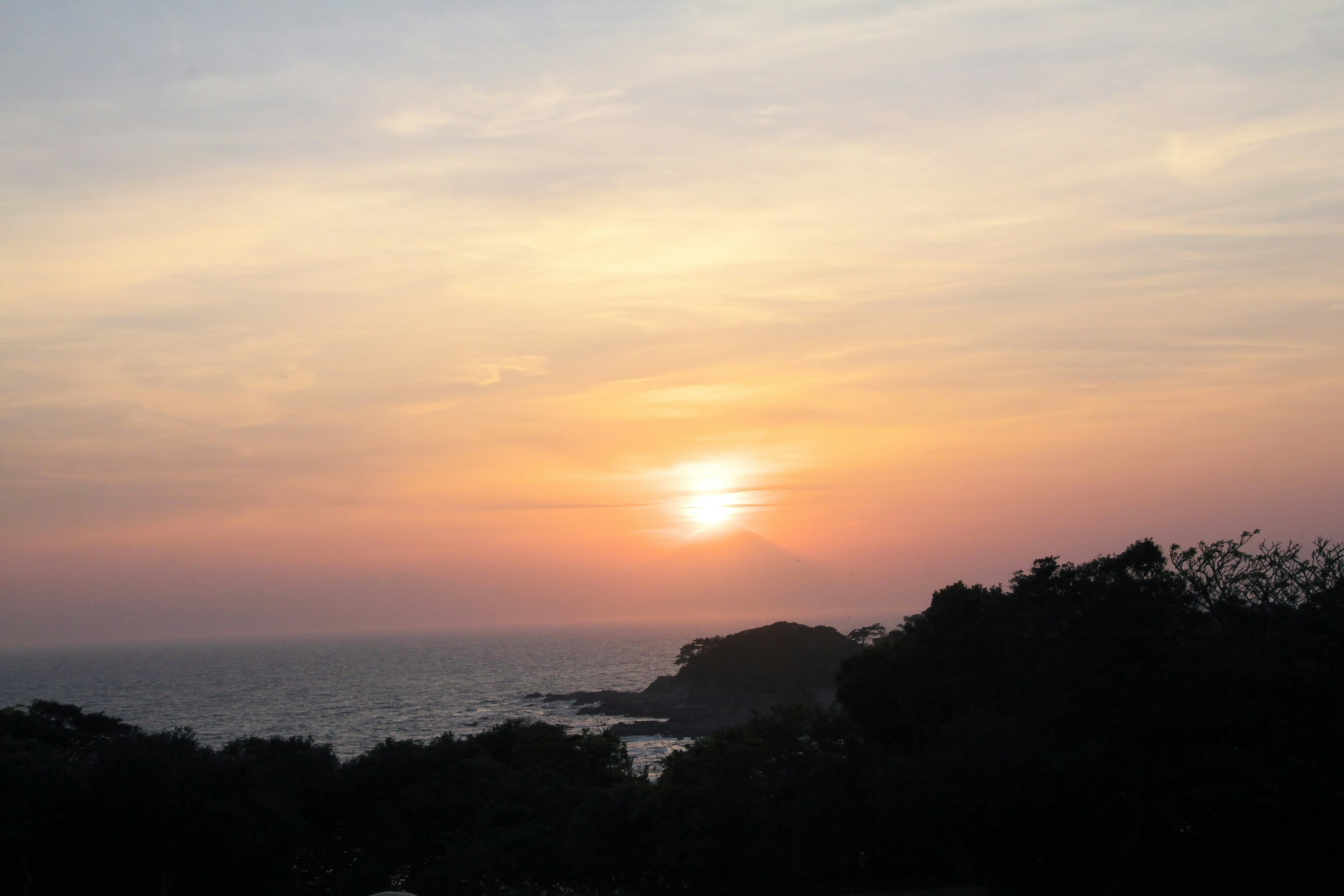 夕日に照らされた海と山並みのシルエット