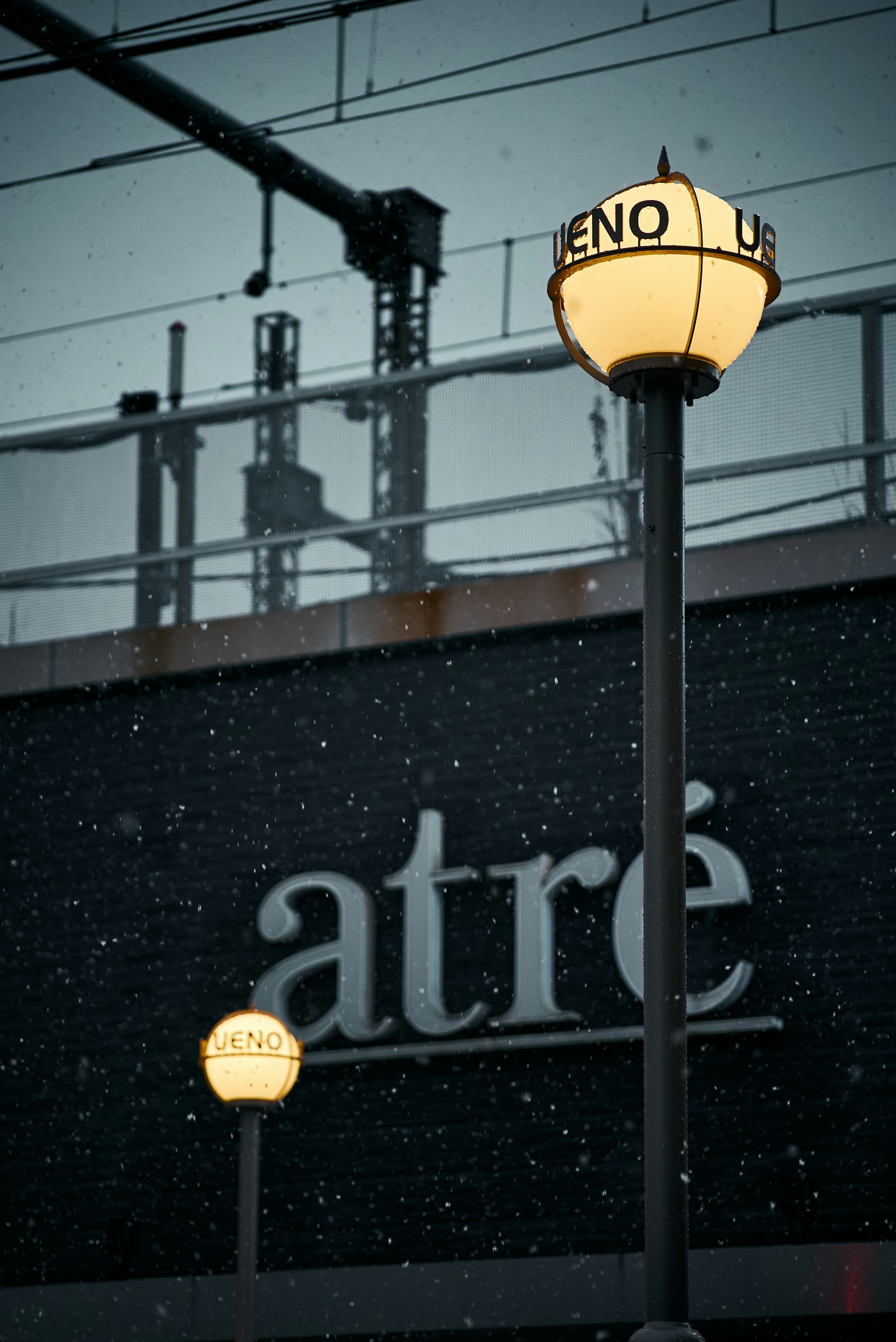 눈 속의 가로등과 검은 벽에 쓰인 'atré'라는 단어
