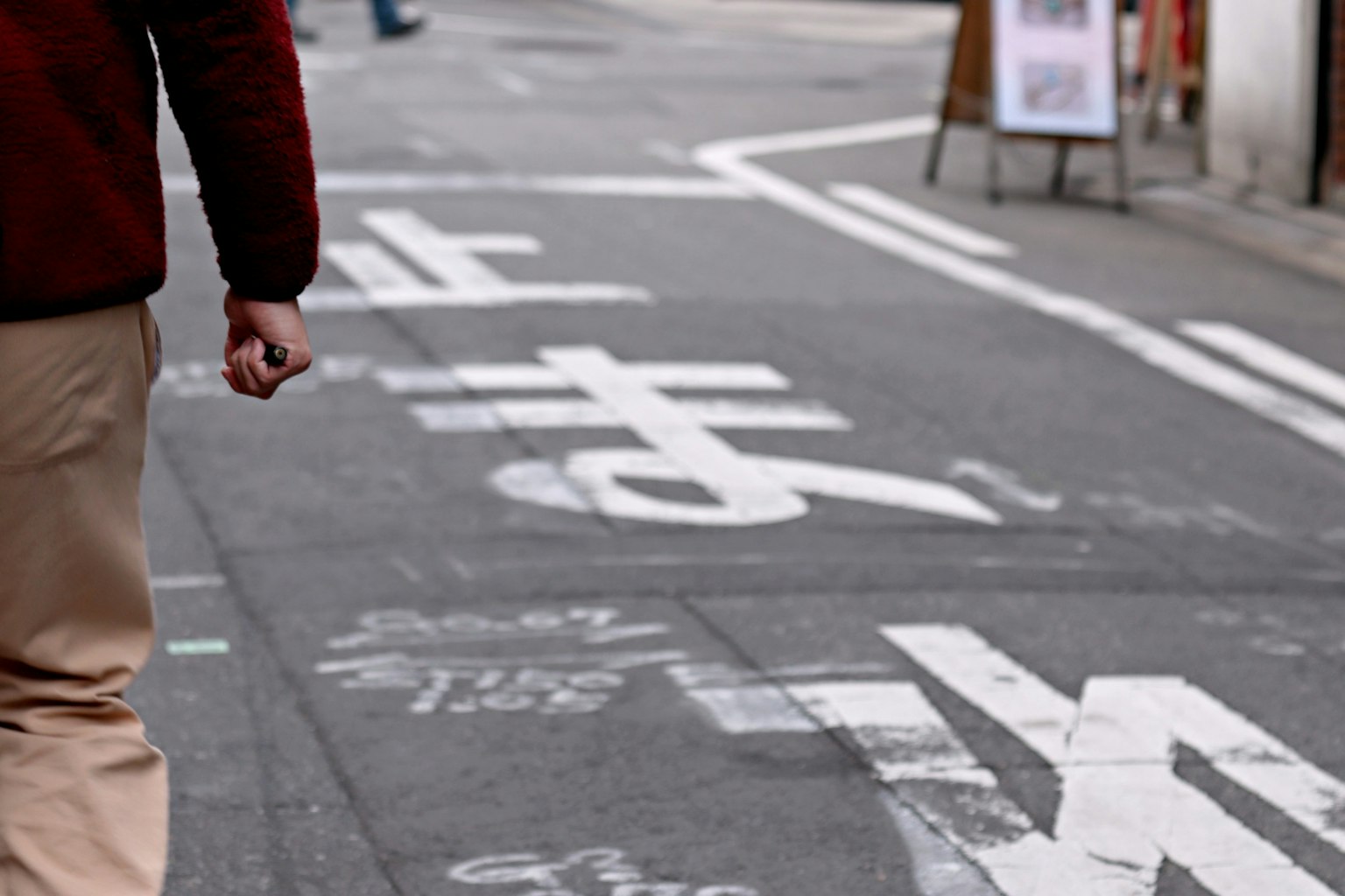 行人在街上走，路面有白色标记和符号