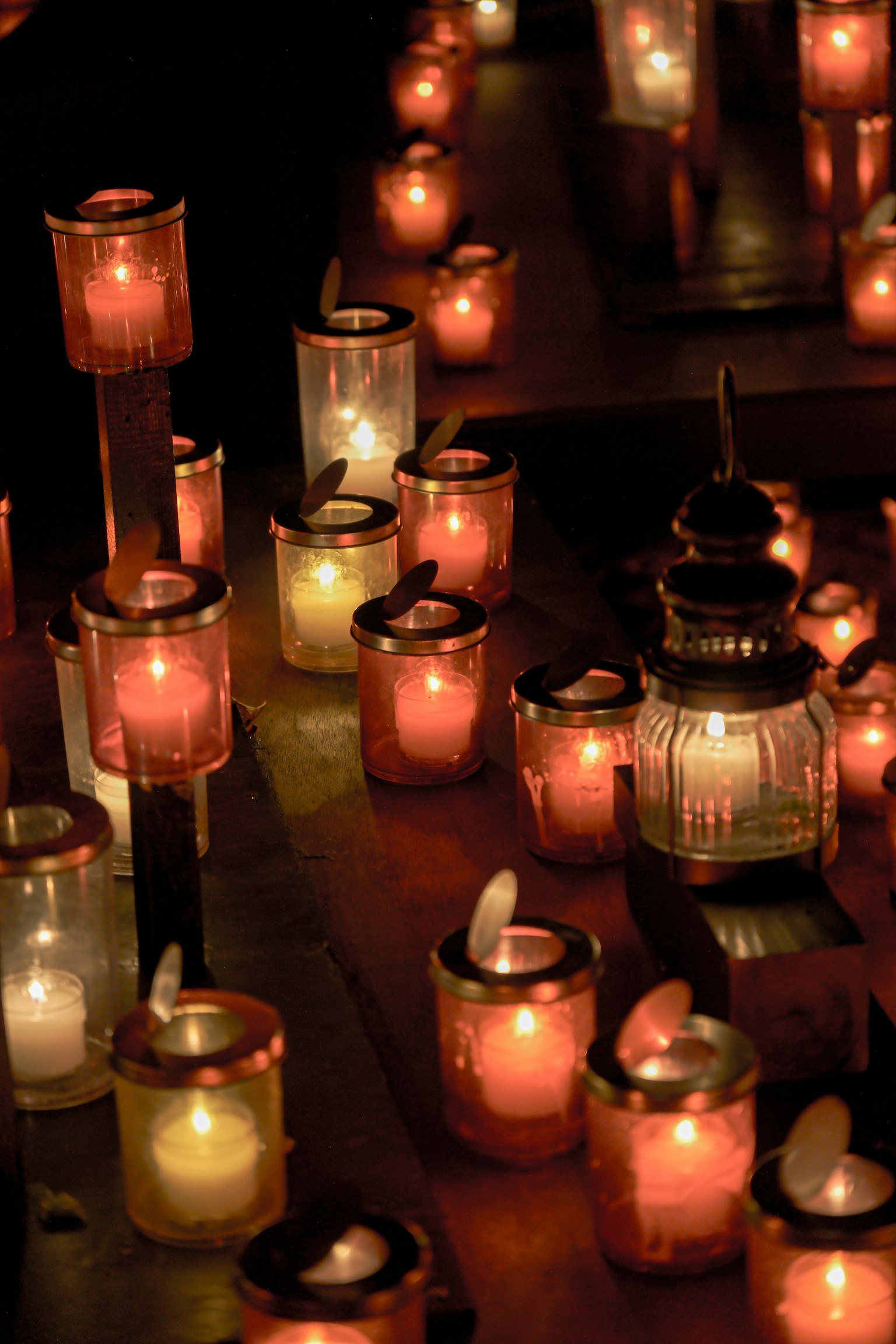 A collection of candles and lanterns glowing in various colors at night
