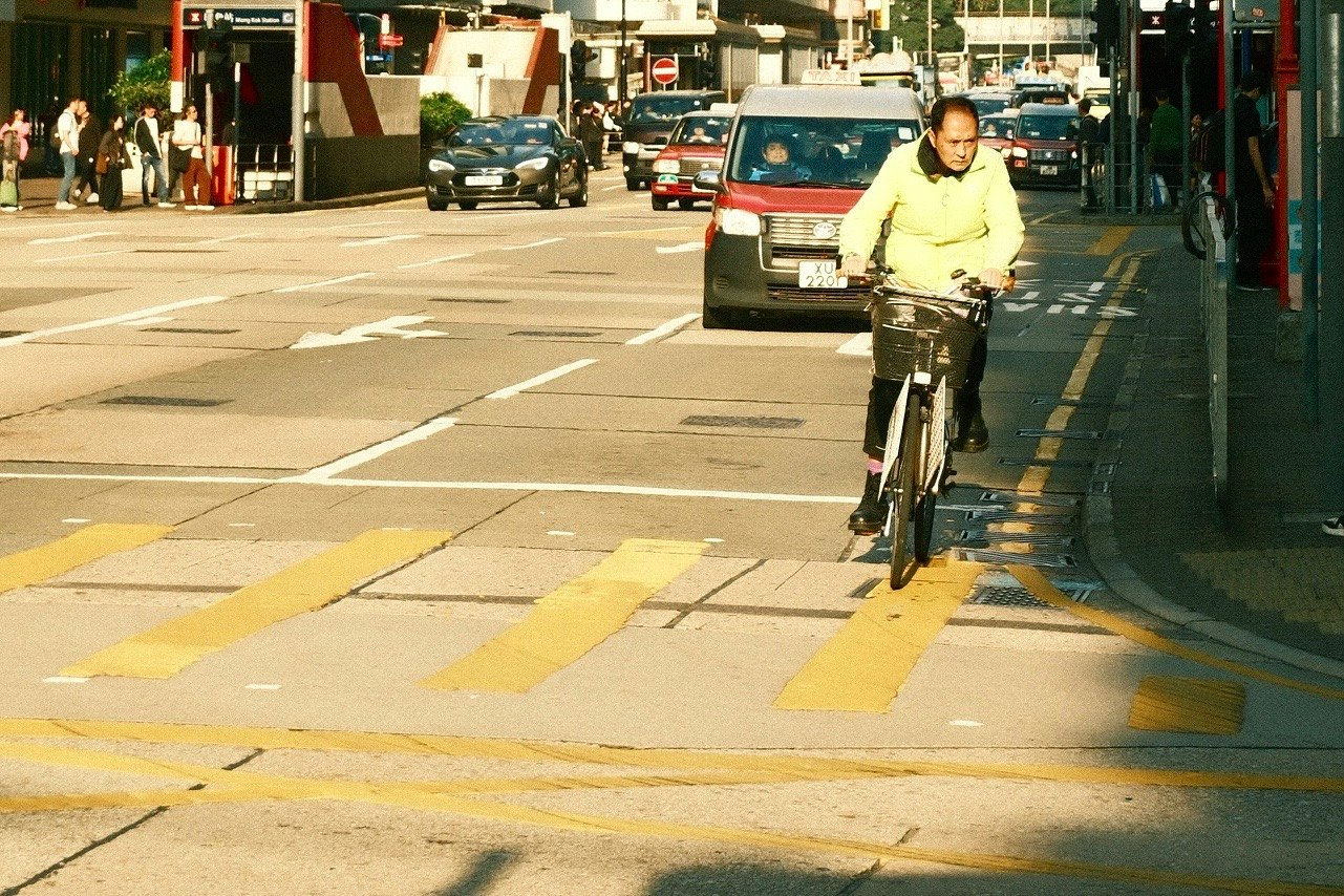 自転車に乗る男性が交差点を渡る様子 車両が通行する街の風景