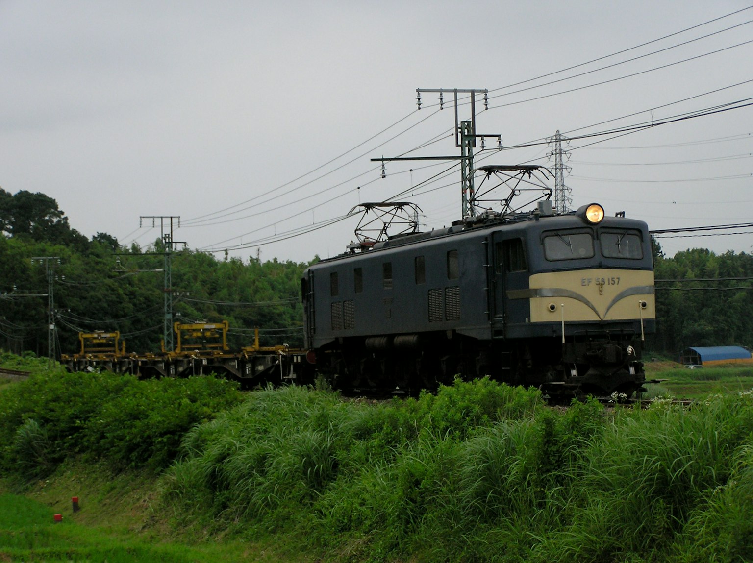 Elektrische Lokomotive und Wartungsfahrzeuge in einer grasbewachsenen Landschaft