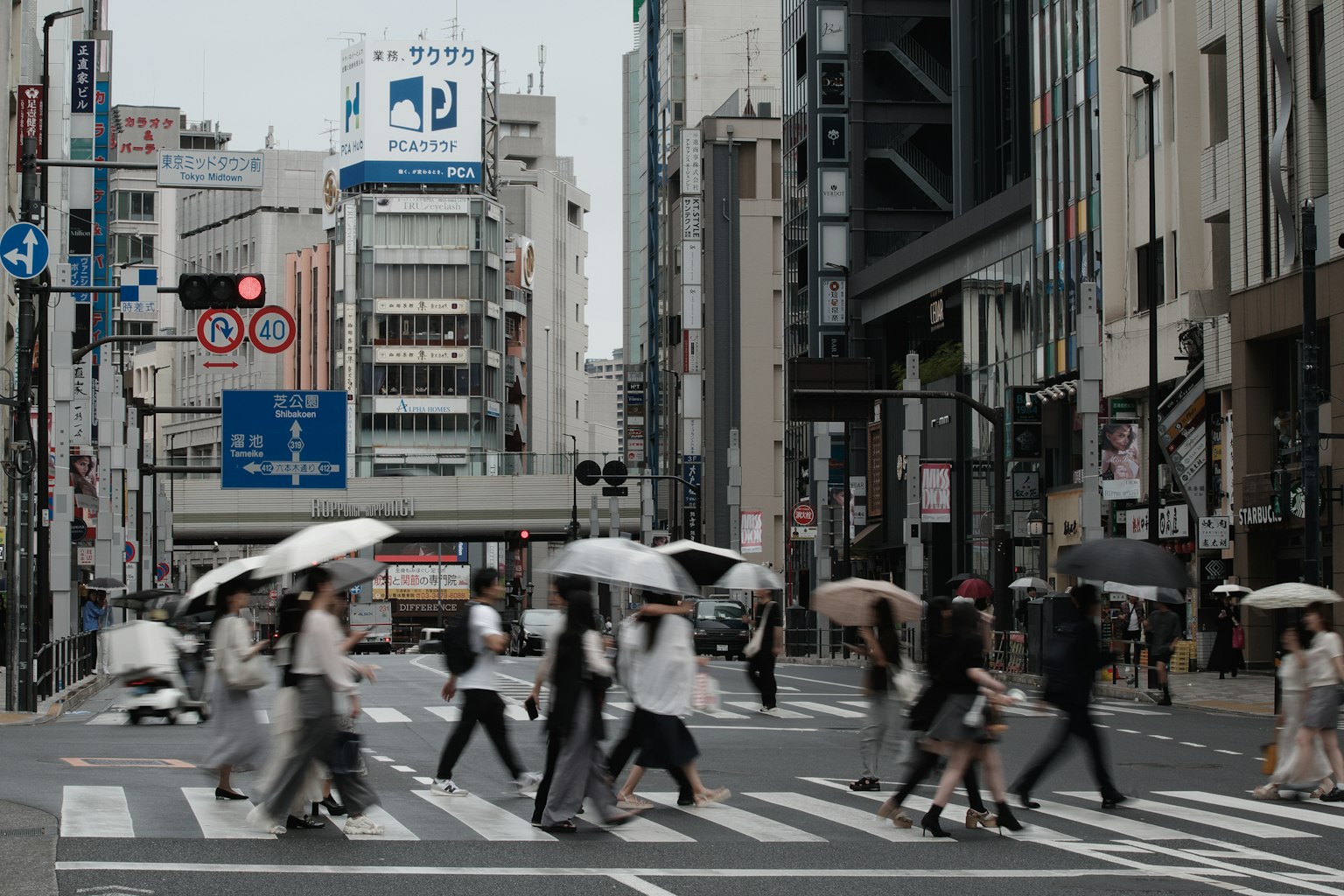 Des personnes avec des parapluies traversent une rue dans un quartier d'affaires
