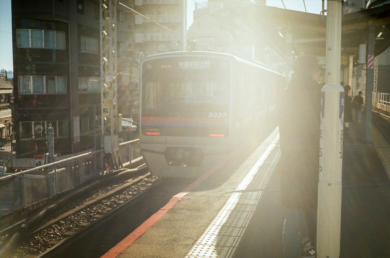 Train arrivant à une gare entouré de lumière vive et de bâtiments