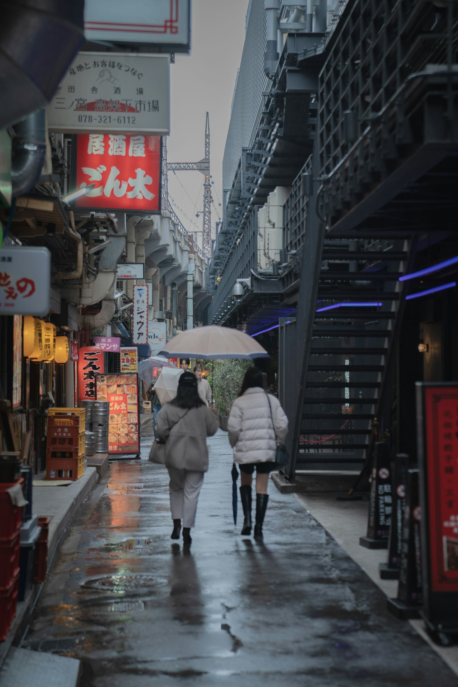 Zwei Frauen, die bei Regen unter einem Regenschirm in einer engen Straße gehen